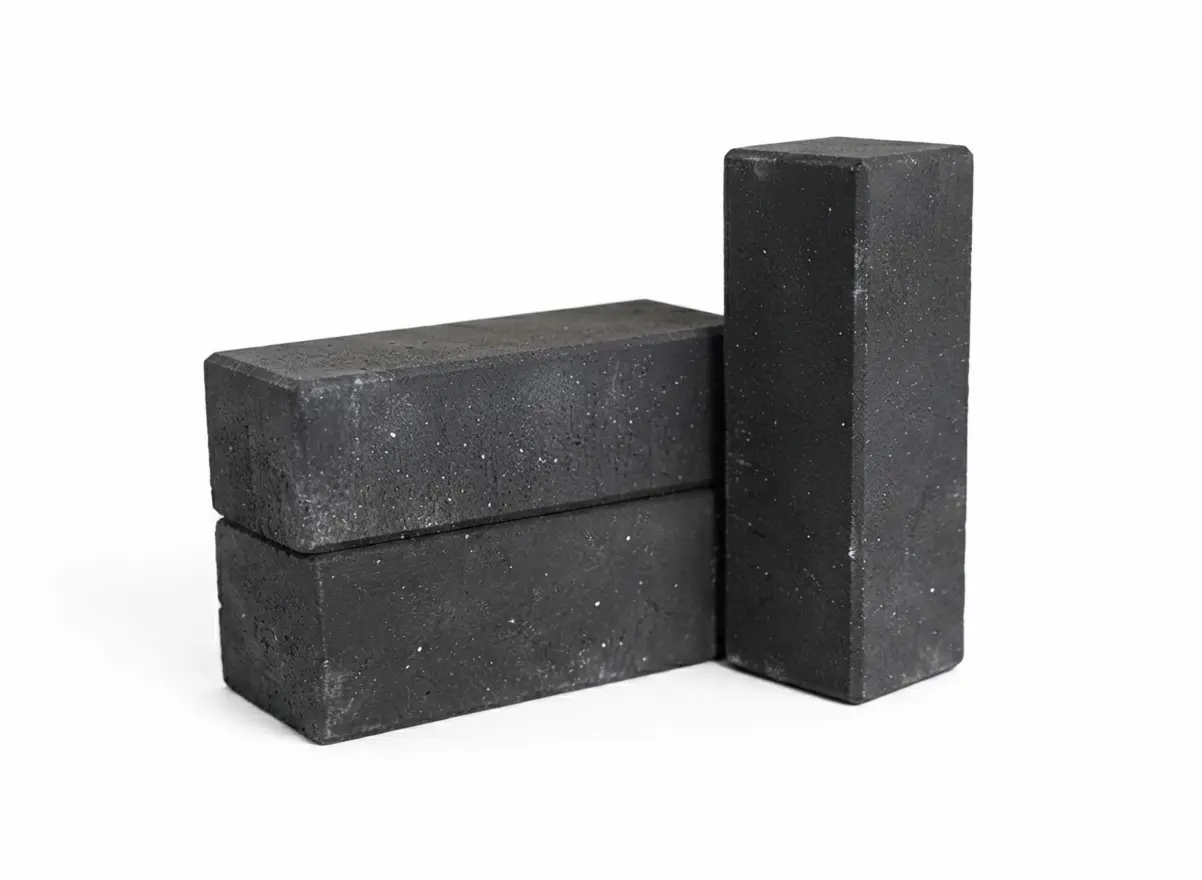 Two dark, rectangular bricks stacked horizontally, with a third standing vertically behind them, a reference for pavers vs travertine.