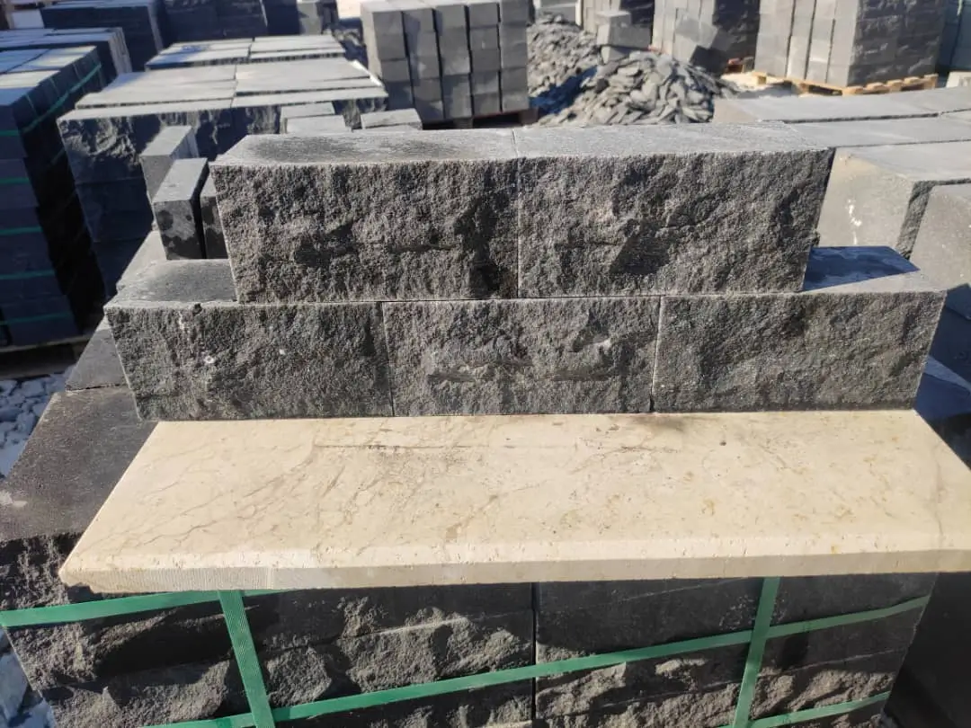Stacked dark gray rough-hewn granite pavers with a beige marble slab on top, shown for round paver stones.