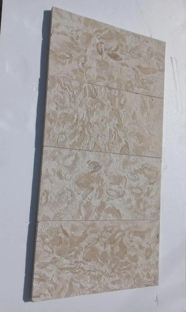 Close-up view of textured beige travertine tiles showing natural veining patterns, shown for how to install rock landscape edging.