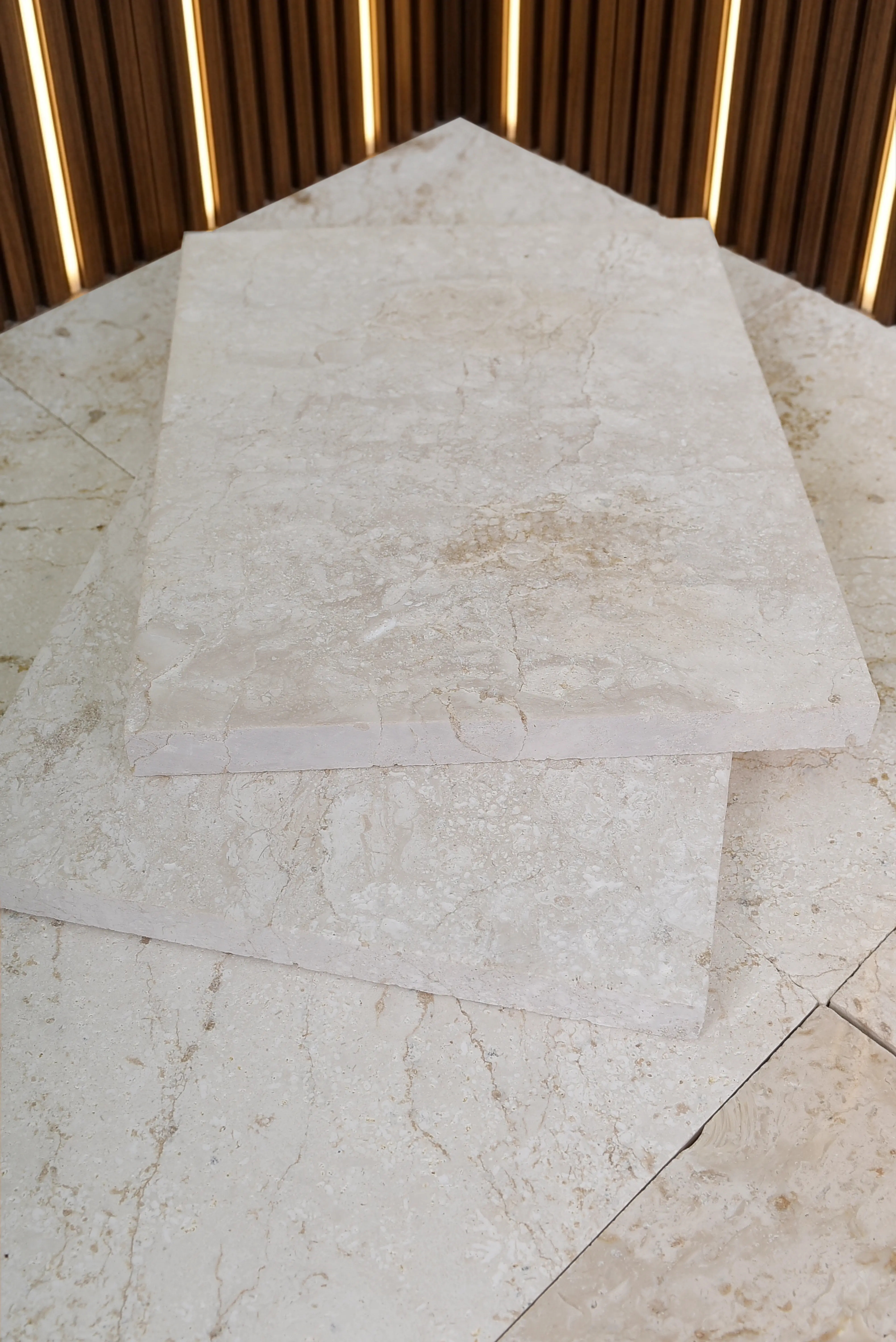 Close-up view of stacked beige travertine slabs showcasing natural veining and texture, an example for natural stone exterior wall.
