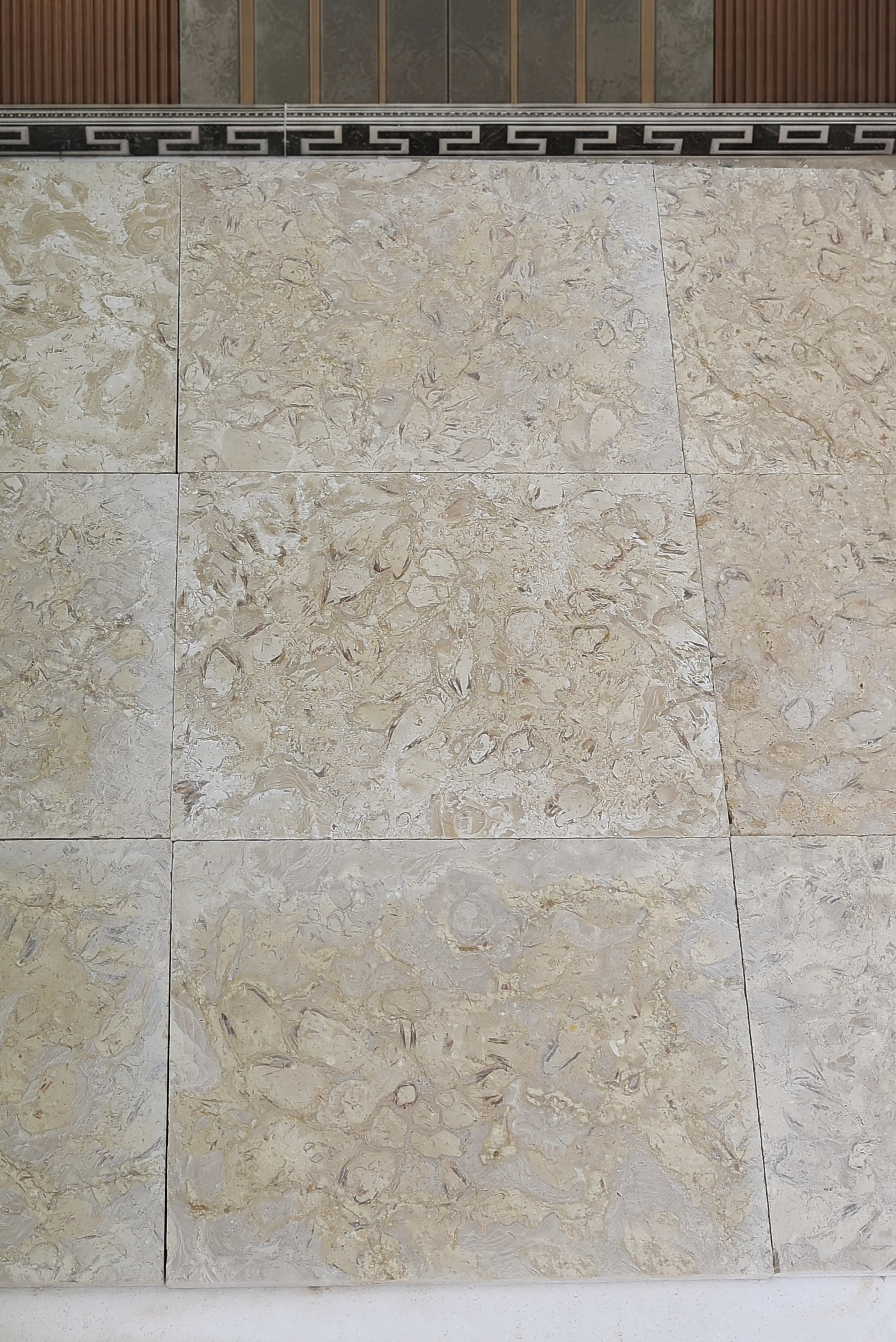 Close-up of beige marble tiles with intricate swirling patterns for flooring, an example for marble edging care.