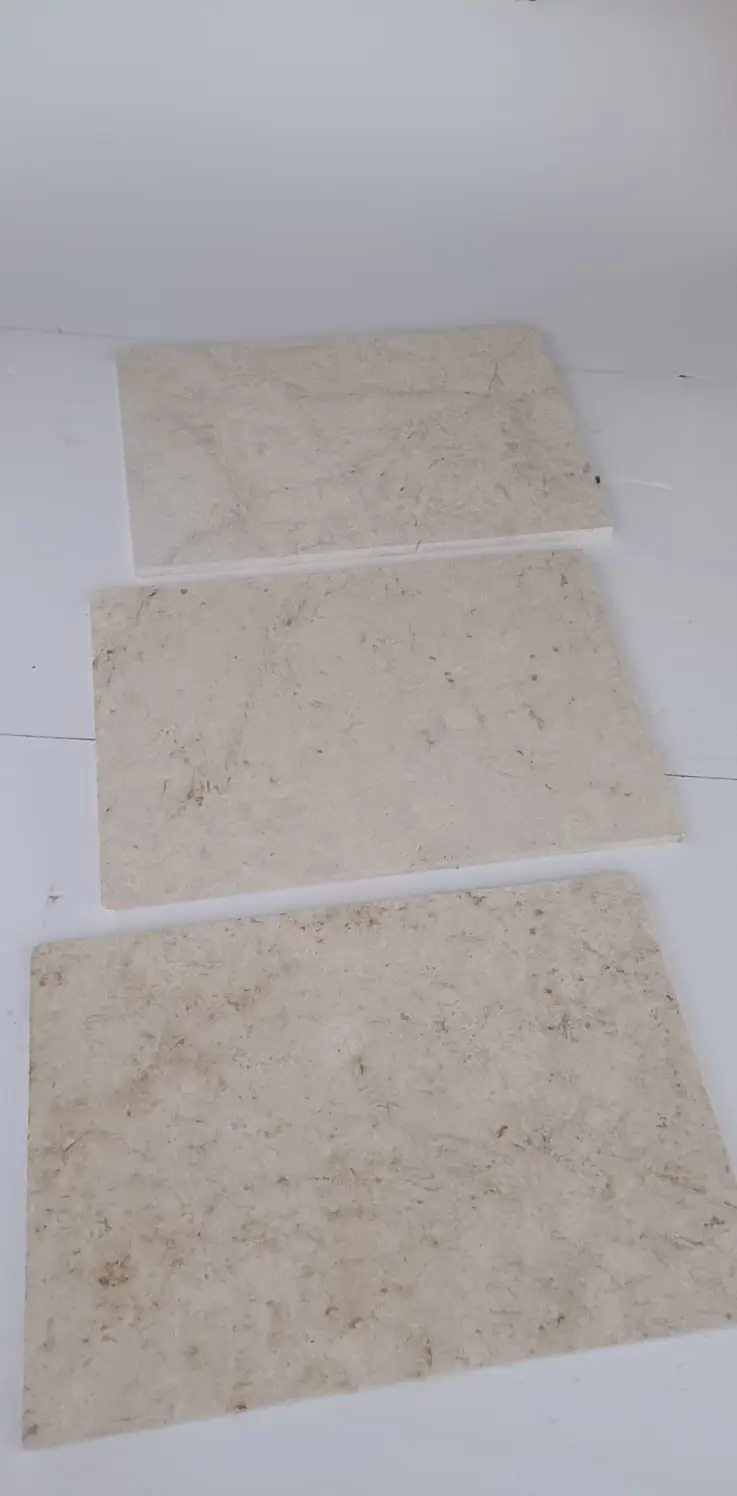 Close-up view of beige limestone tiles with natural veining and speckles, a reference for remnant granite slabs vs full slabs.