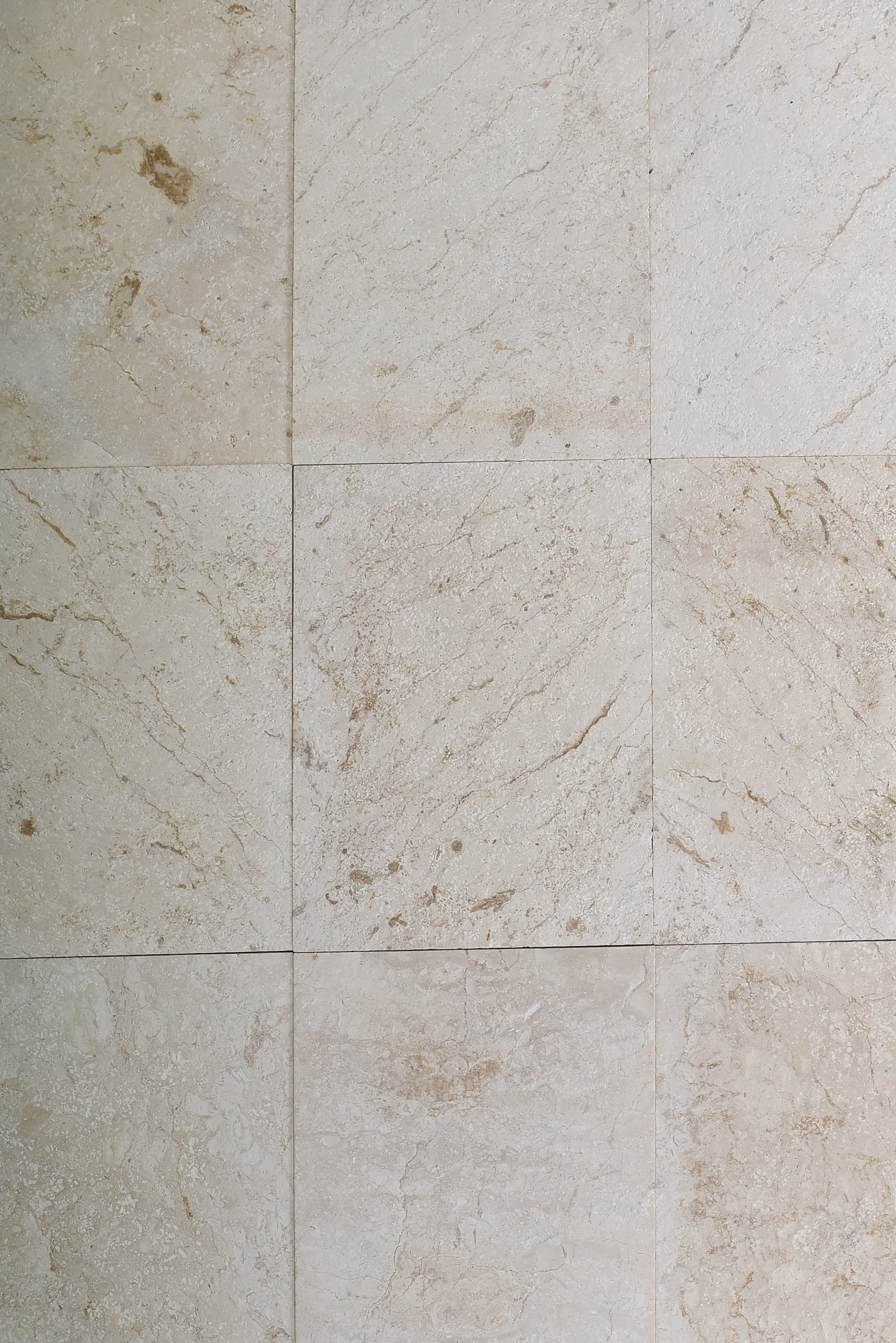 Close-up of beige travertine tiles showcasing natural veins and subtle texture, pictured for cheapest paving stones.