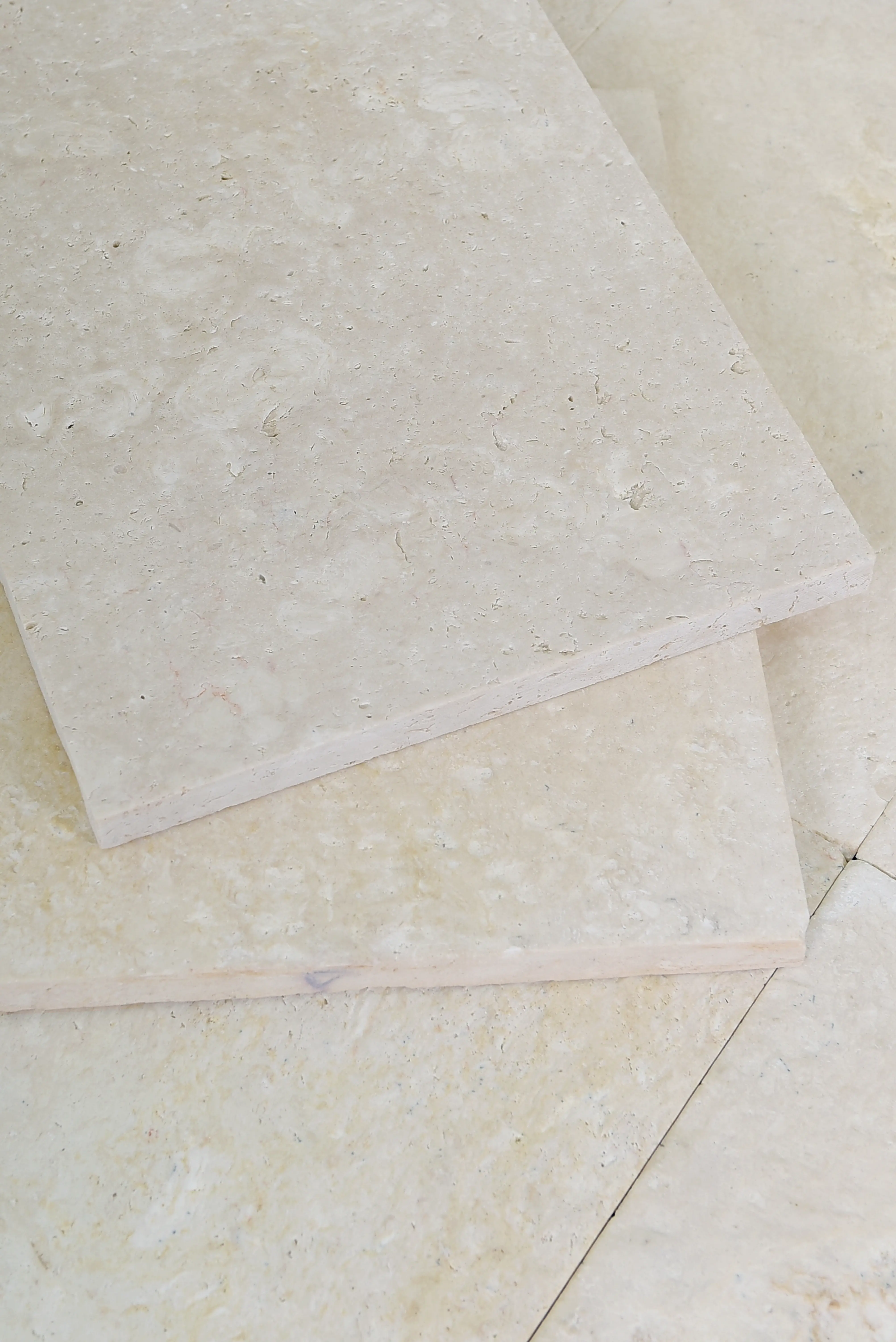 Close-up texture of beige travertine tiles showing subtle veining and small natural pores, shown for how do you clean travertine tile.