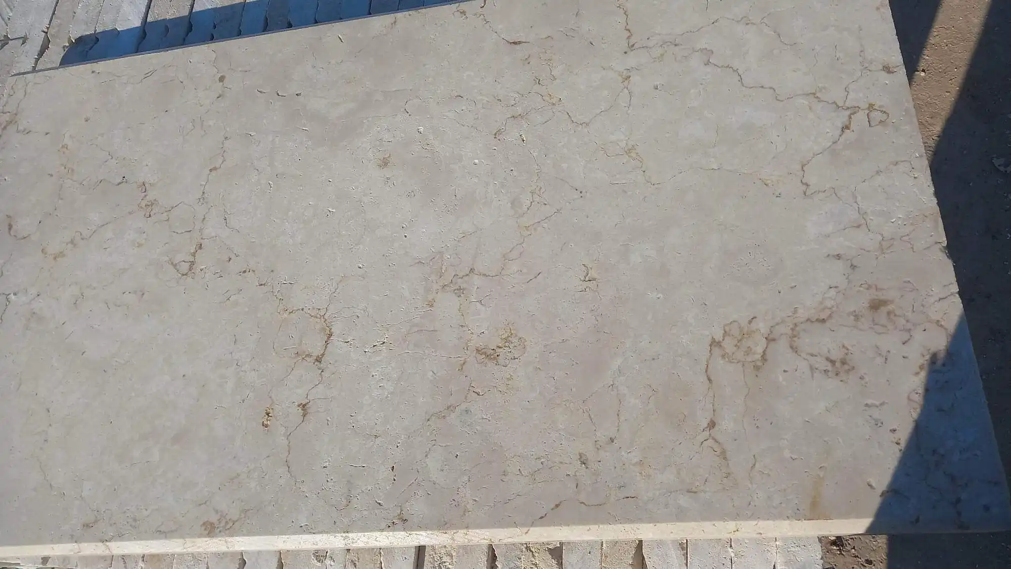 Beige travertine slab with natural brown veining patterns for flooring and wall applications, pictured for stacked flagstone fireplace.