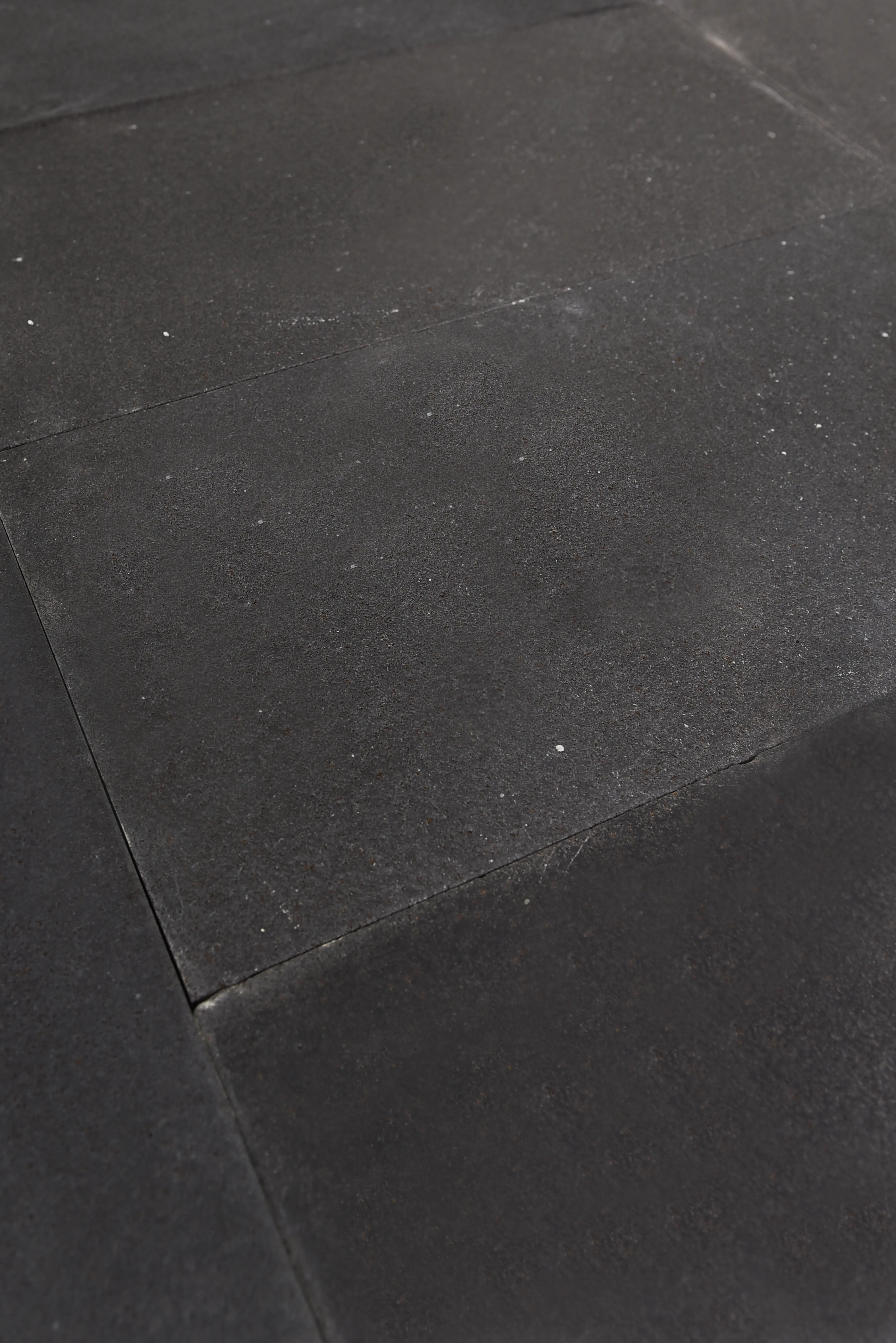 Dark Bluestone Paving Slabs Close-up Close-up texture of dark bluestone pavers showing rough surface and grout lines, pictured for how to choose bluestone grade.