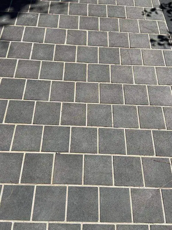 Close-up of dark gray basalt pavers laid in a running bond pattern with light grout, a reference for bluestone vs granite steps.