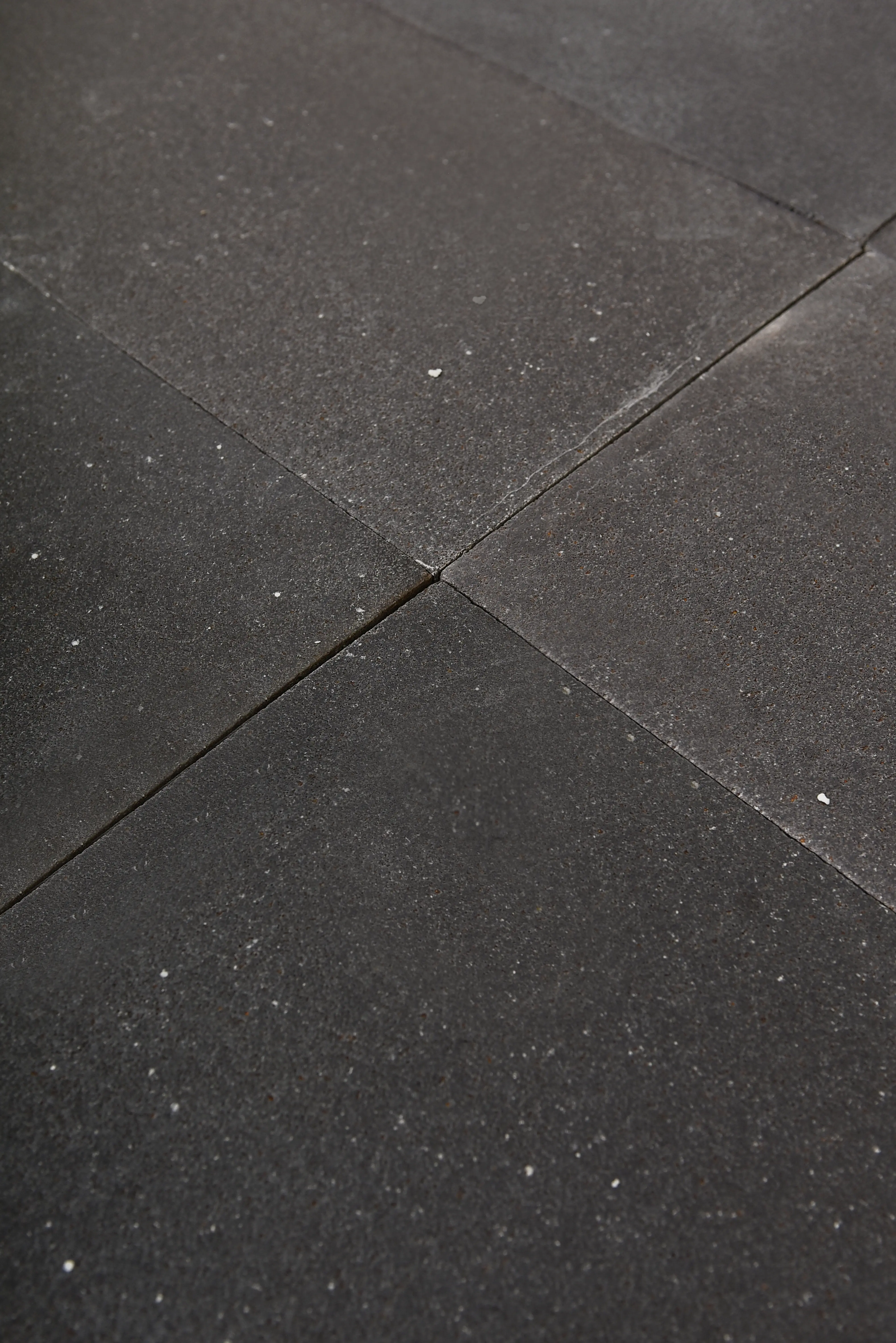 Close-up of dark basalt pavers showing a rough texture with subtle white flecks, a reference for choose paver base material.