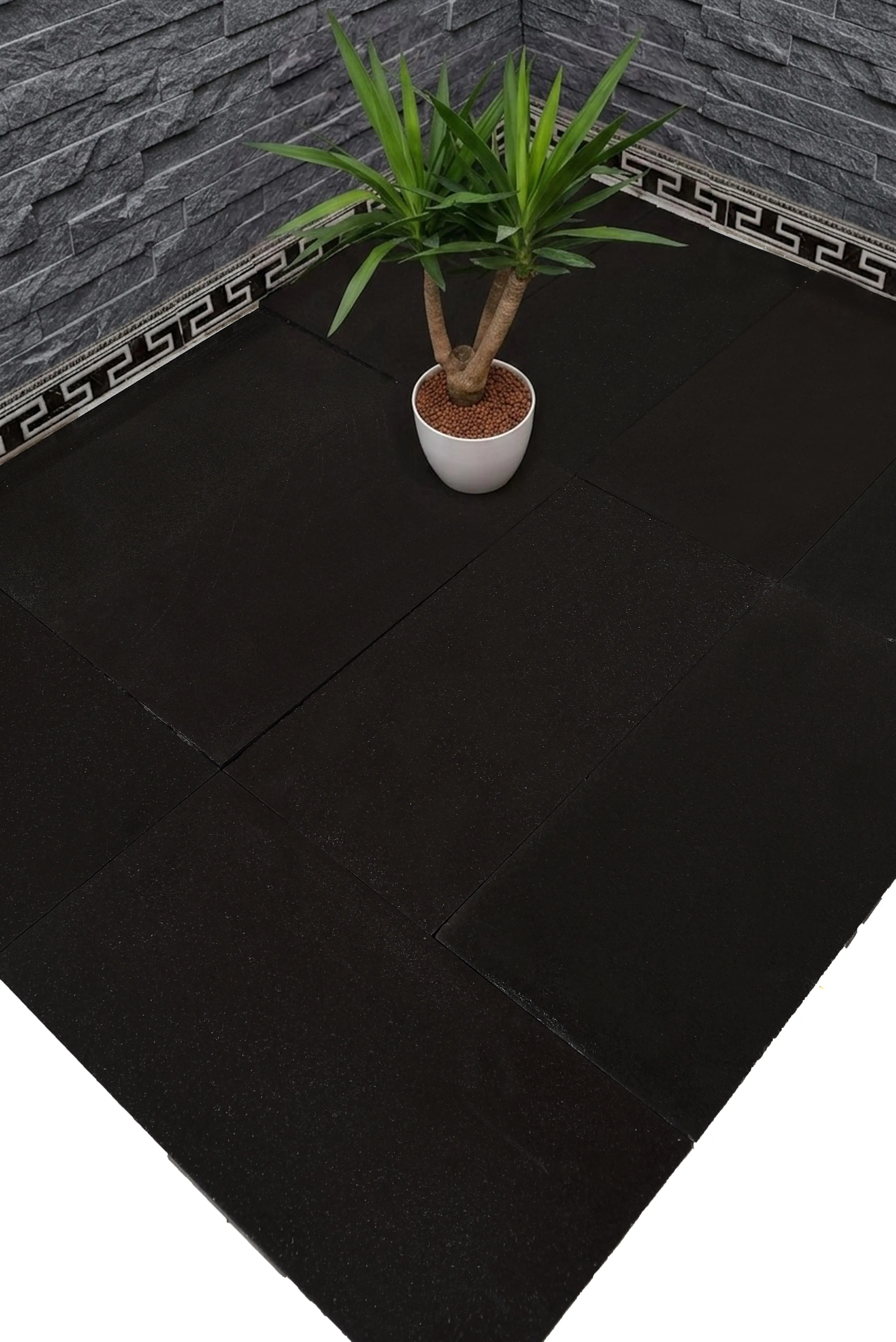 Close-up view of dark textured paving stones with a potted plant, relevant to types of patio stones.
