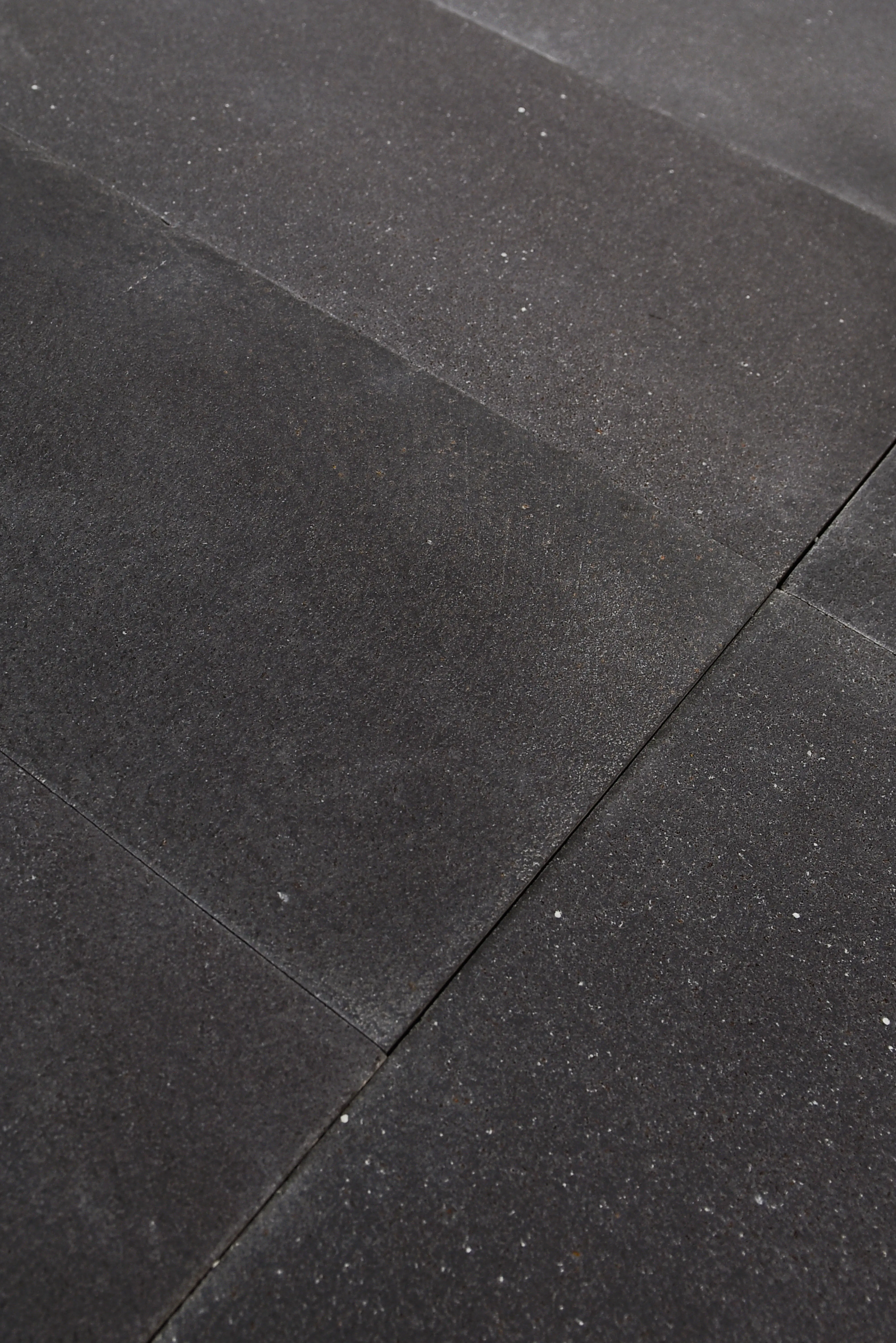 Dark Stone Paver Texture Close-Up Close-up view of dark limestone pavers showing textured surface and grout lines, relevant to jura blue limestone.