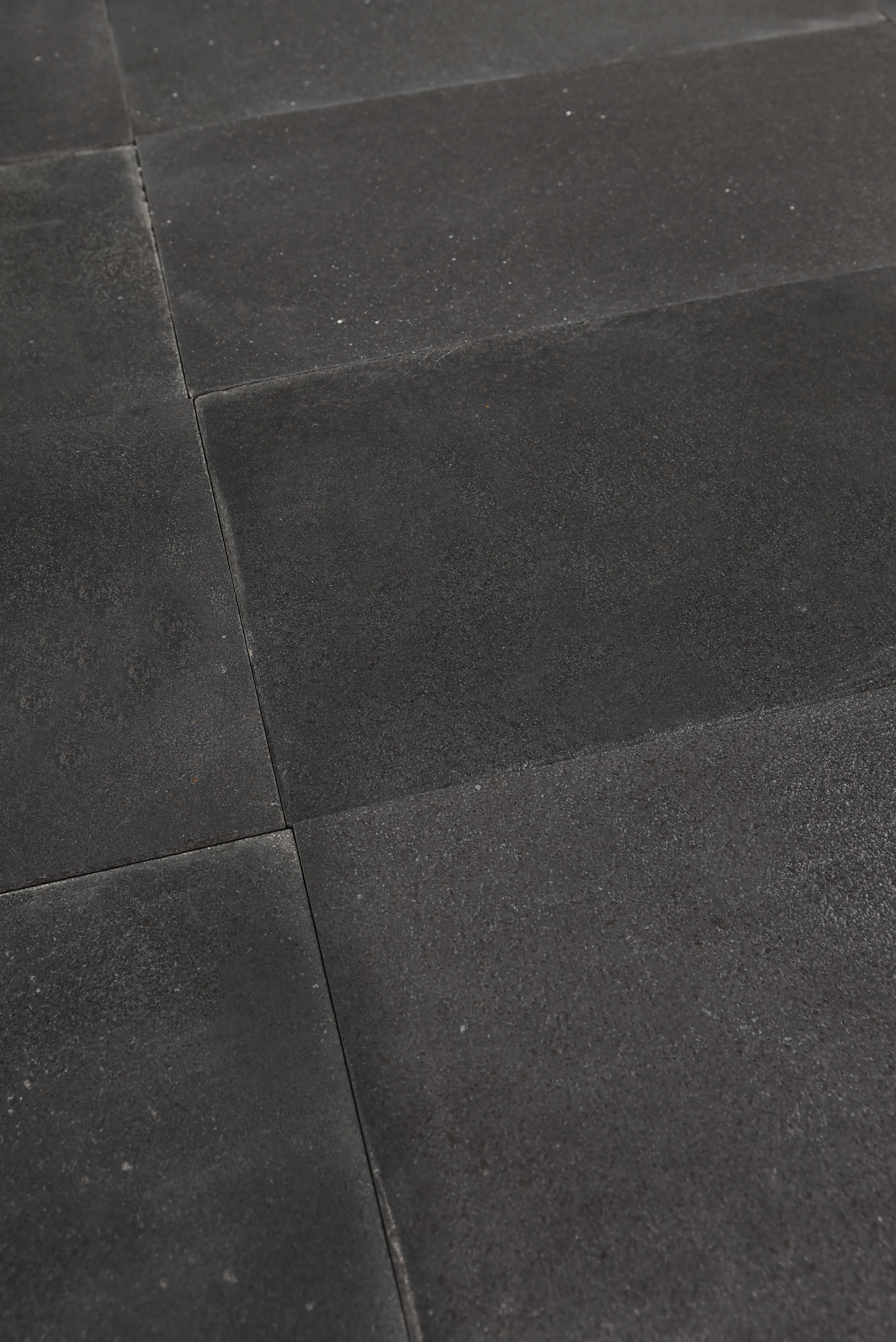 Close-up view of dark limestone pavers with visible texture and grout lines, an example for belgian blue limestone flooring.