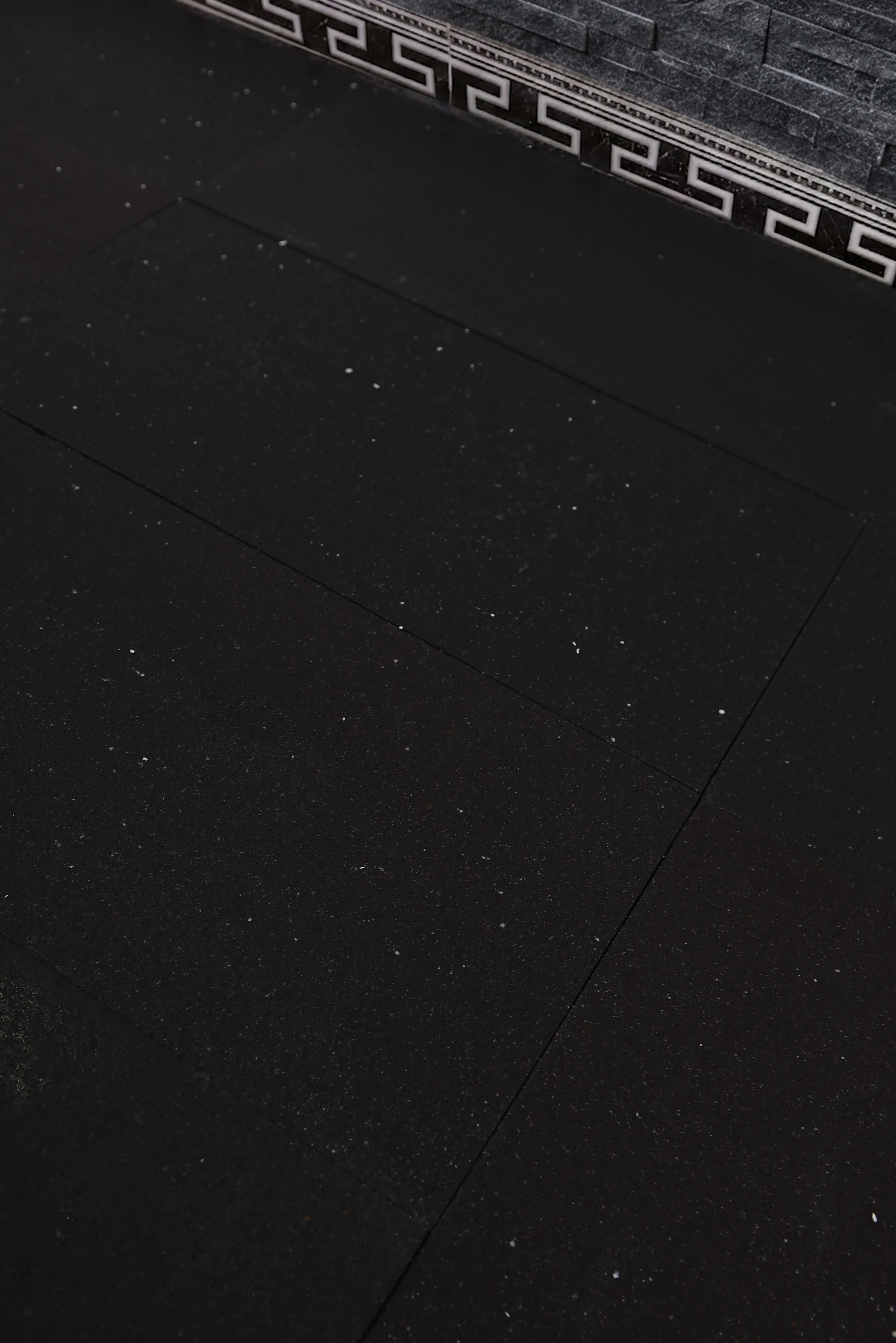 Dark Textured Flooring With Speckles Dark speckled floor tiles showing a textured surface and clean grout lines, a reference for grey limestone blocks buyers guide.