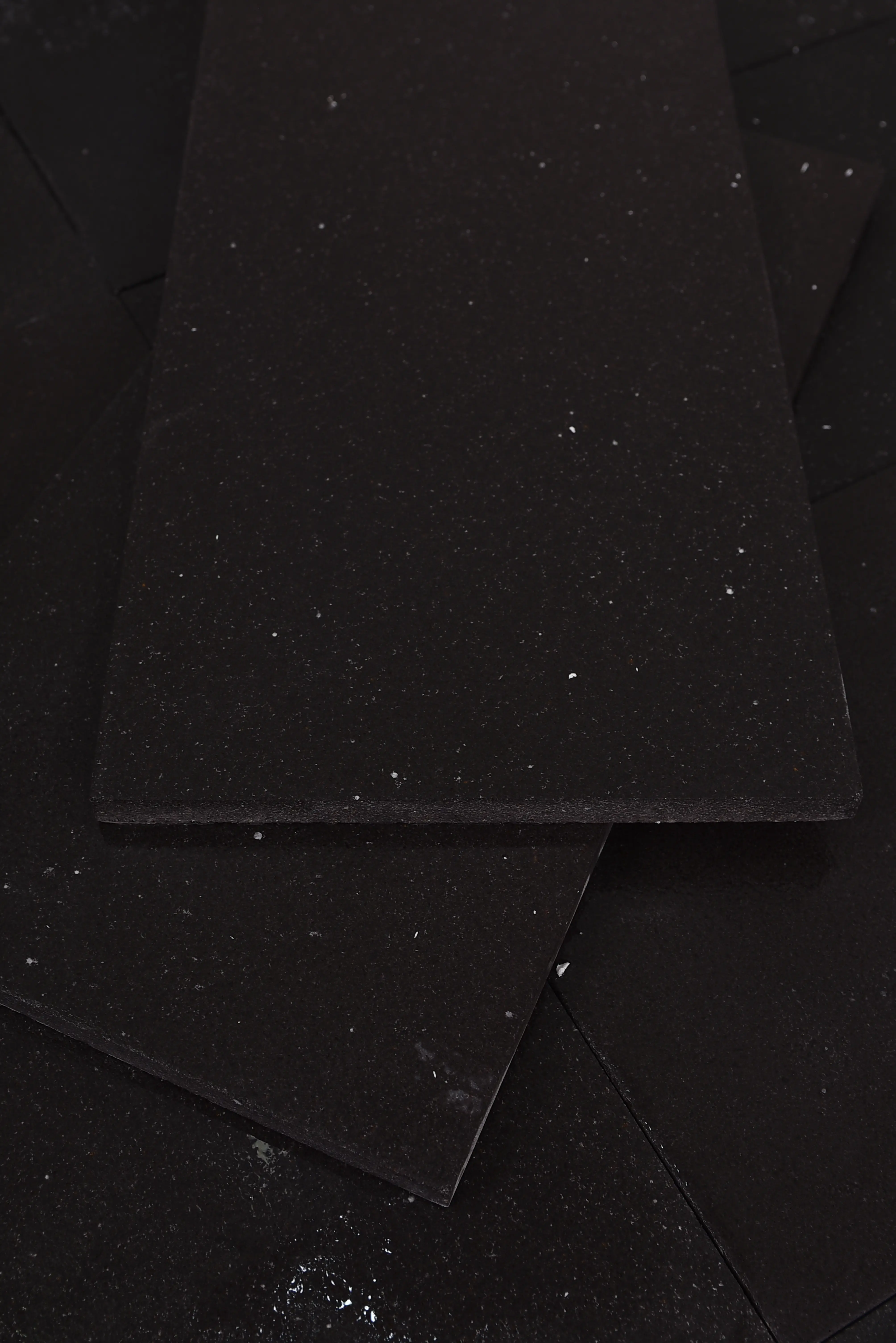 Dark Textured Granite Slabs Stacked Close-up of speckled dark granite pavers showing a textured surface detail, a reference for grey limestone color guide.