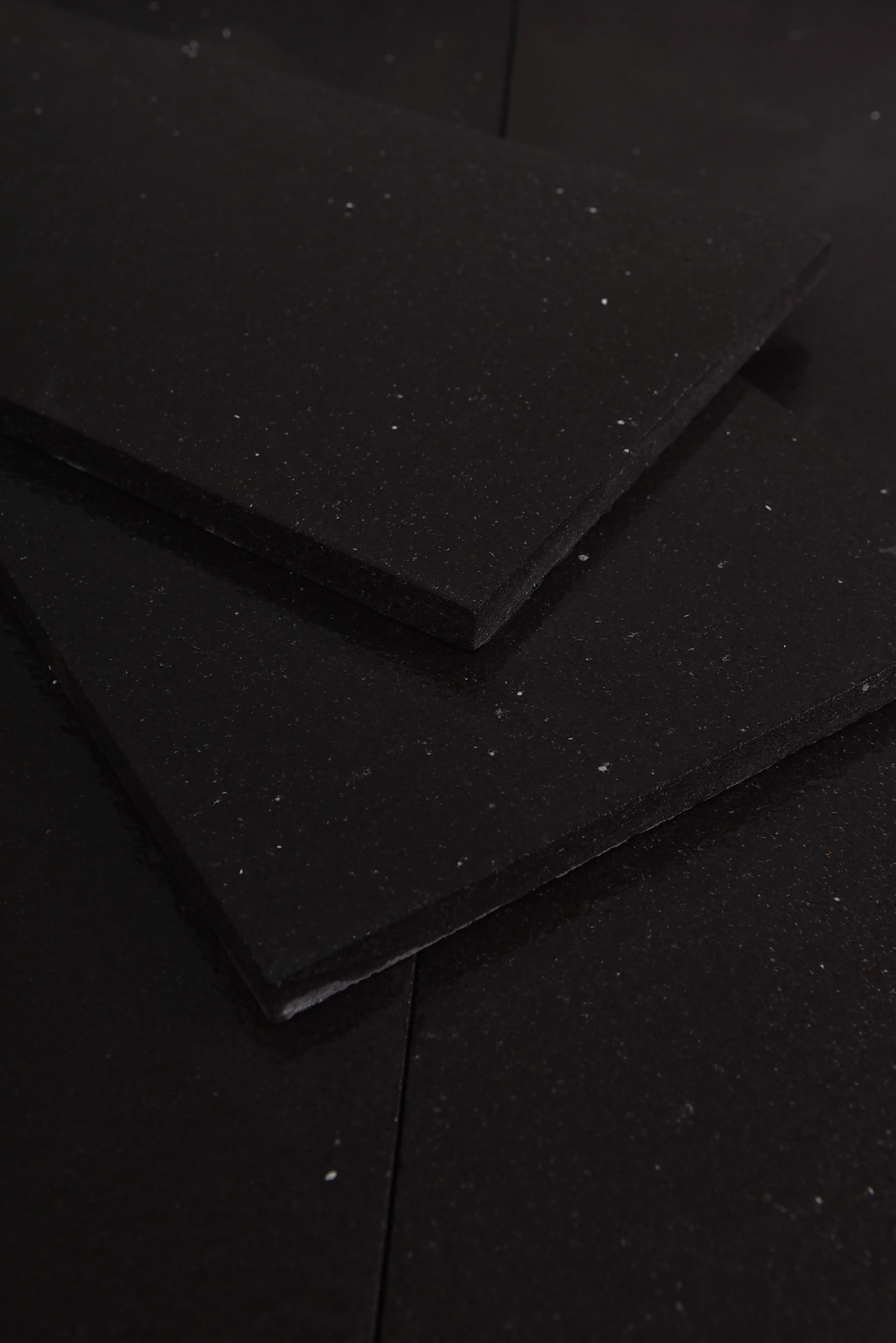 Thin dark textured material slabs are stacked in a layered arrangement, pictured for jerusalem grey gold limestone.