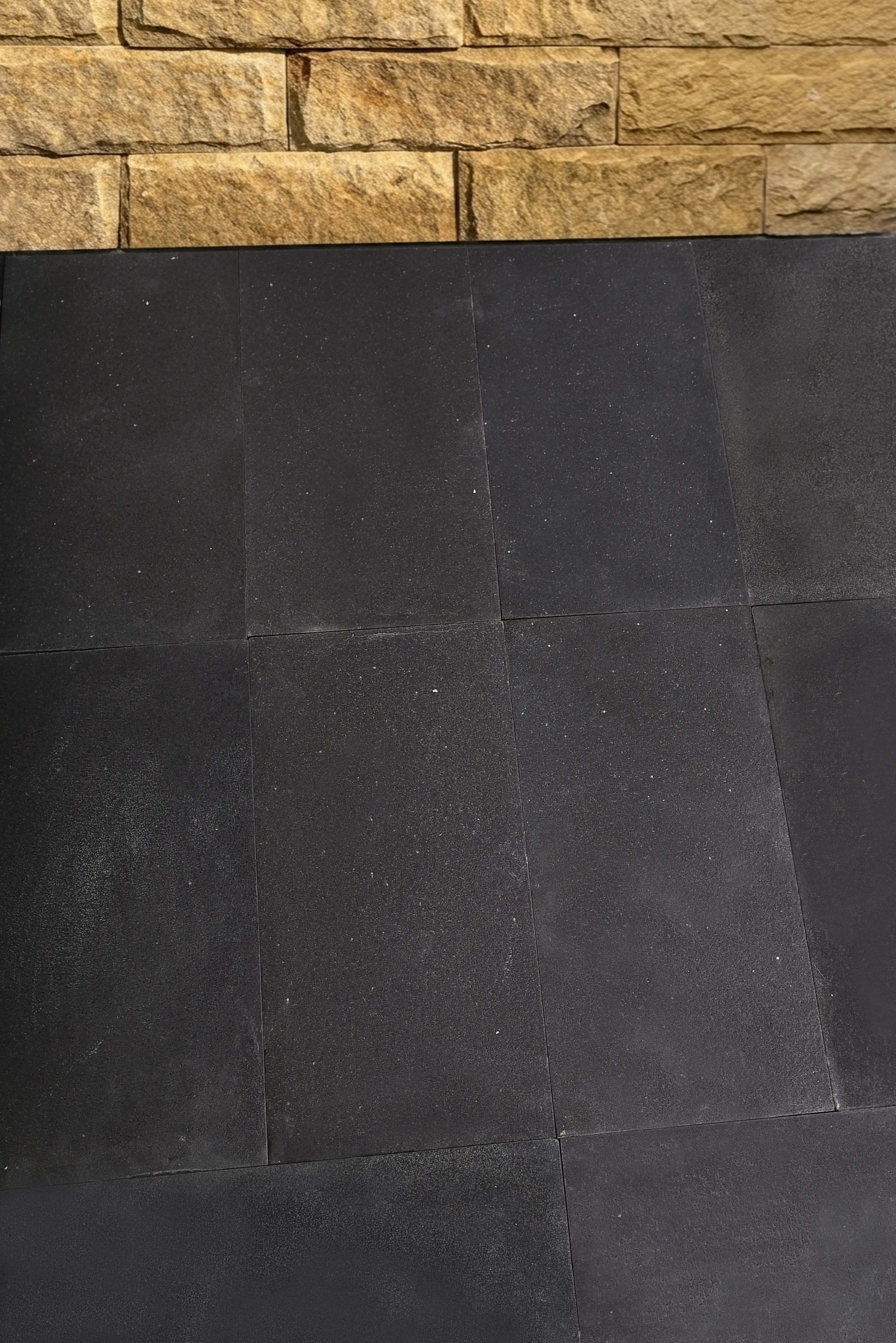 Dark square pavers display a fine-grained texture, offering a durable surface, an example for 6x12 Travertine Tile.