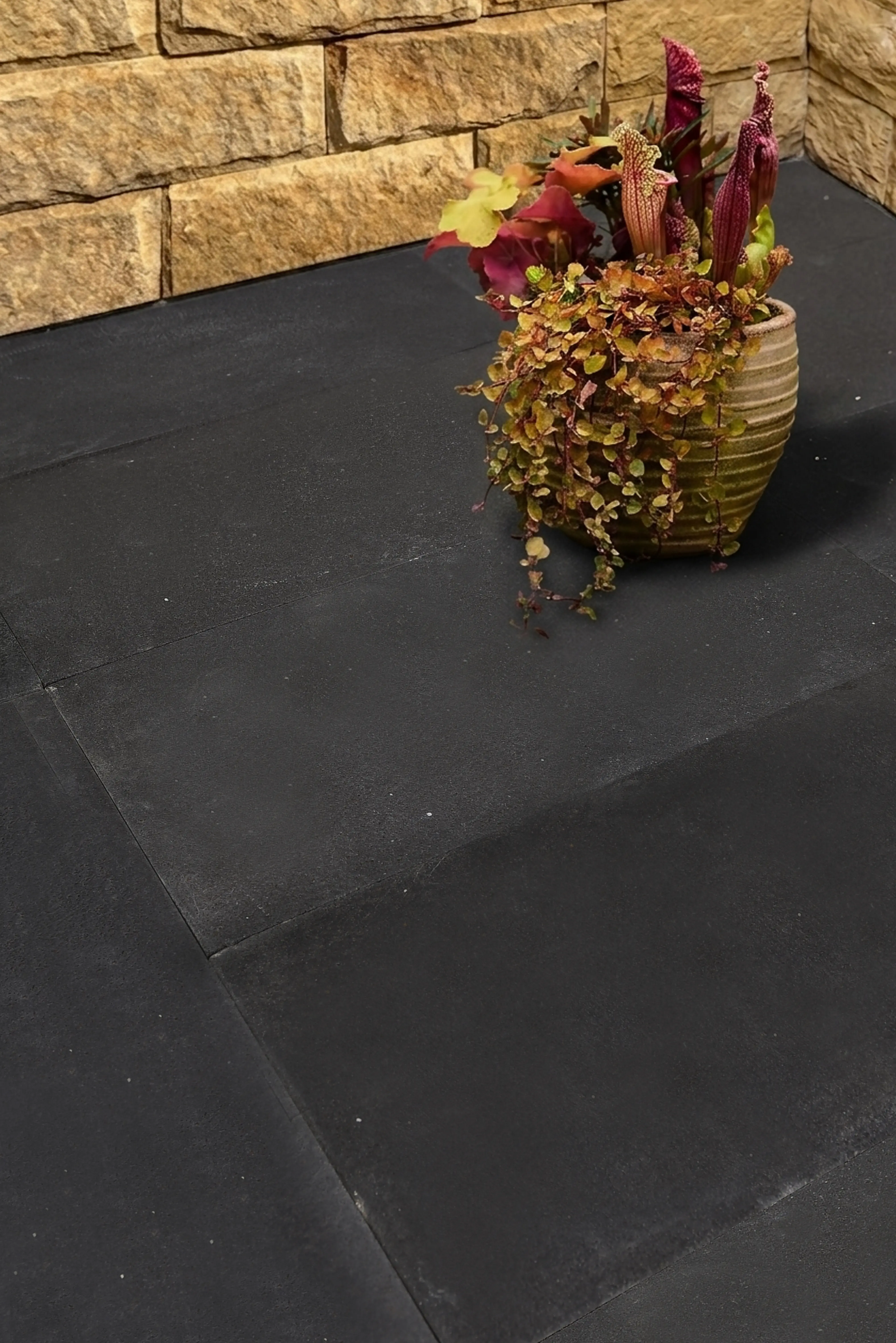 Potted plants with red and yellow foliage sit on dark stone pavers, an example for Granite Products.