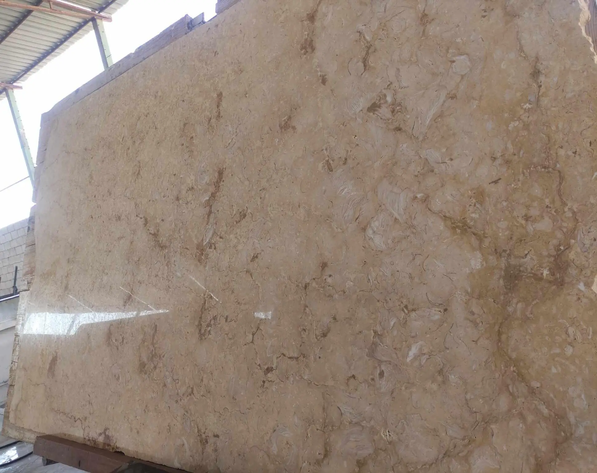 Beige limestone slab with natural swirling patterns and brown veining, a reference for slipform stone masonry method.