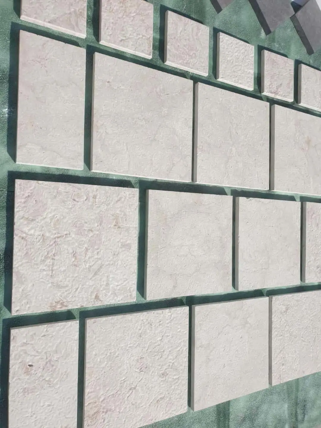 Stacked light-colored limestone tiles showing natural surface texture and variations in sunlight, shown for flagstone walkway ideas.
