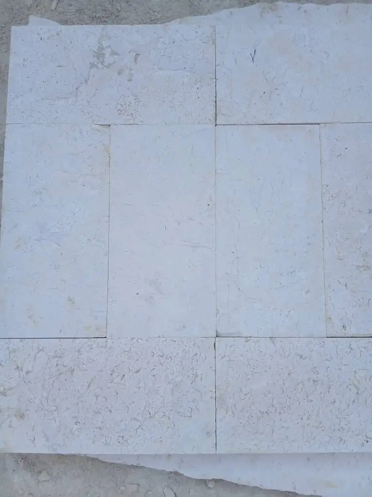 Close-up of light cobblestone tiles laid in a staggered pattern on a floor surface, pictured for cobblestone paver patterns.