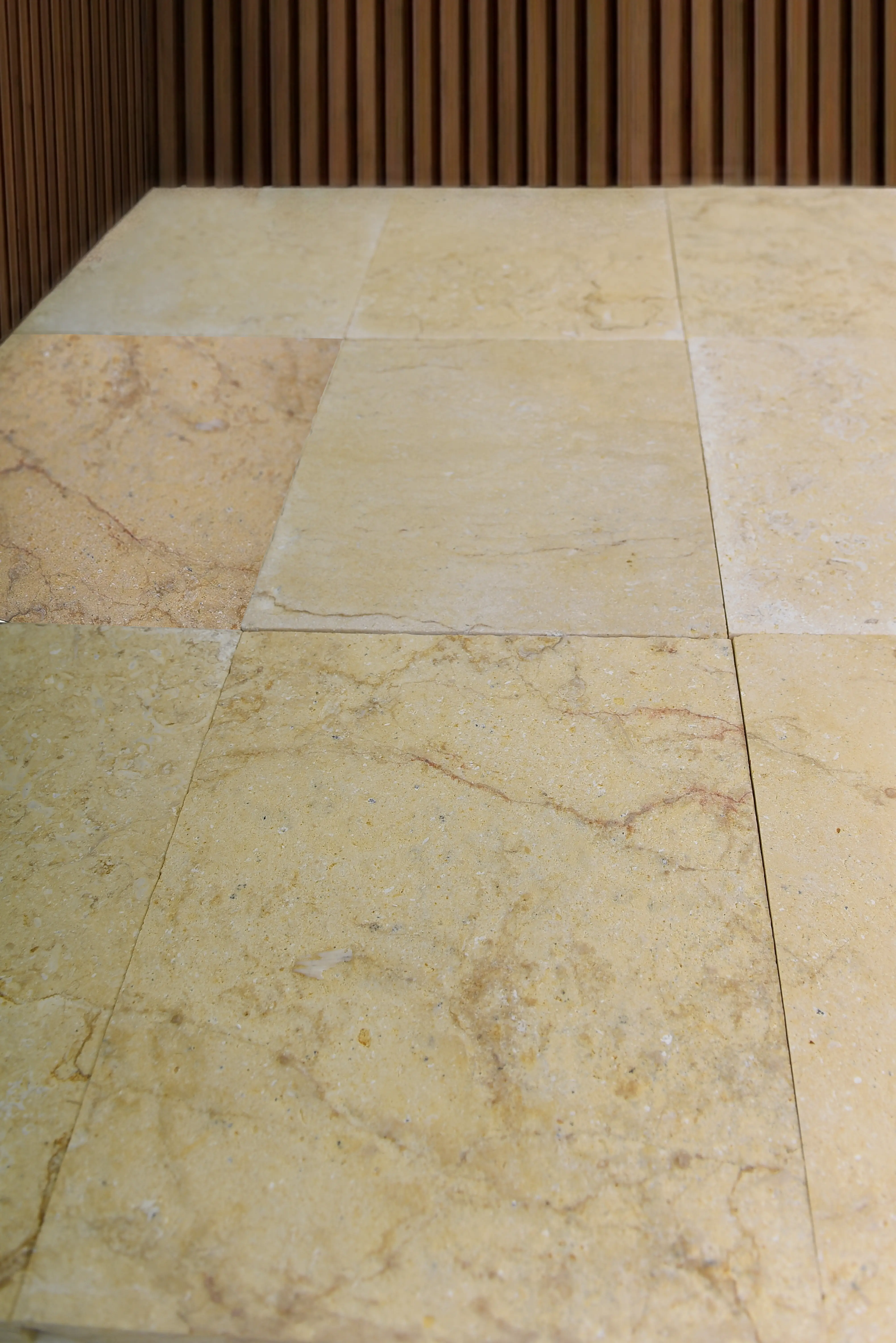 Close-up of light beige marble floor tiles with natural veining and subtle texture, a reference for kerb stones.