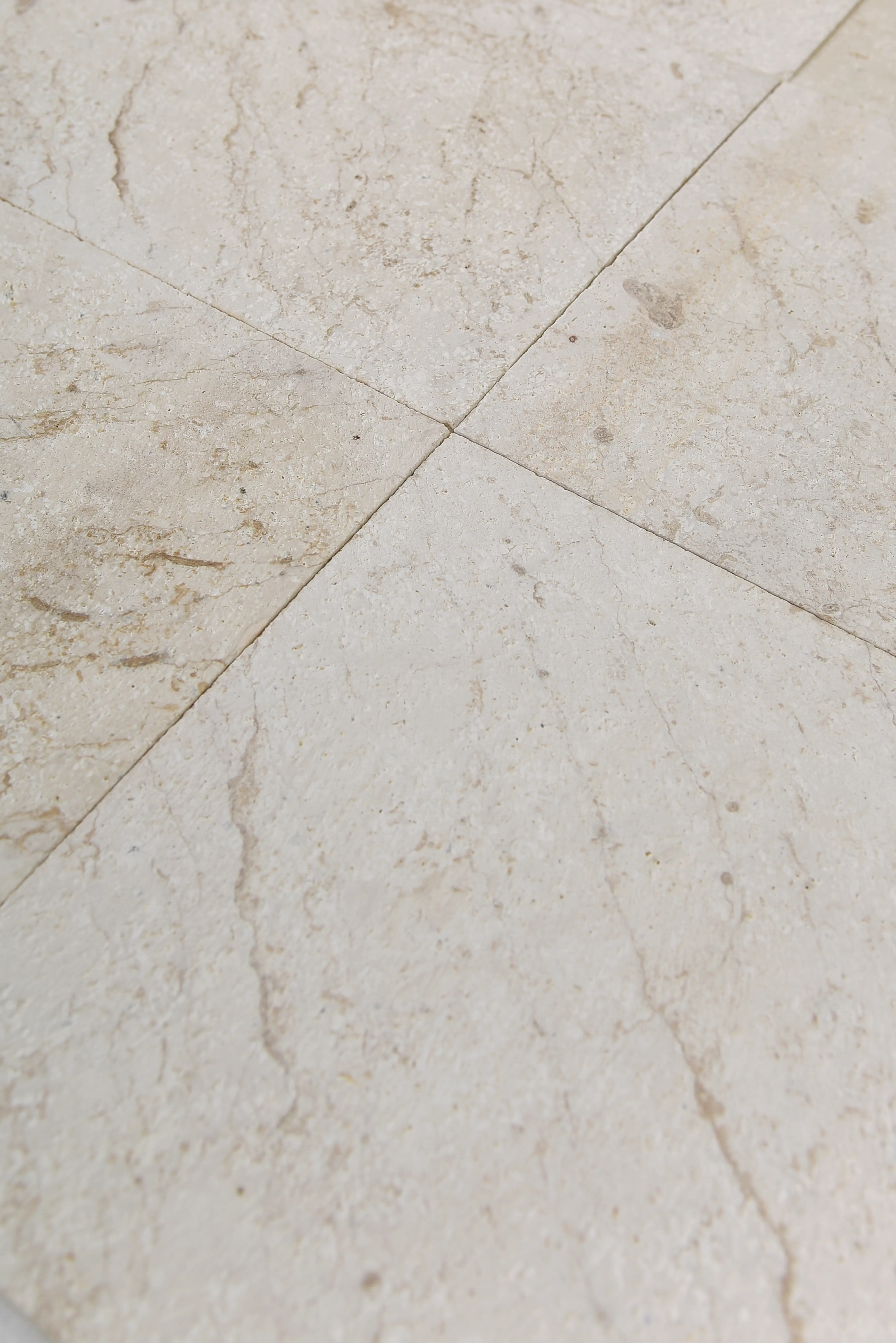 Close-up texture of light cream marble tile flooring showing natural veining patterns, an example for how to use landscape stone glue.