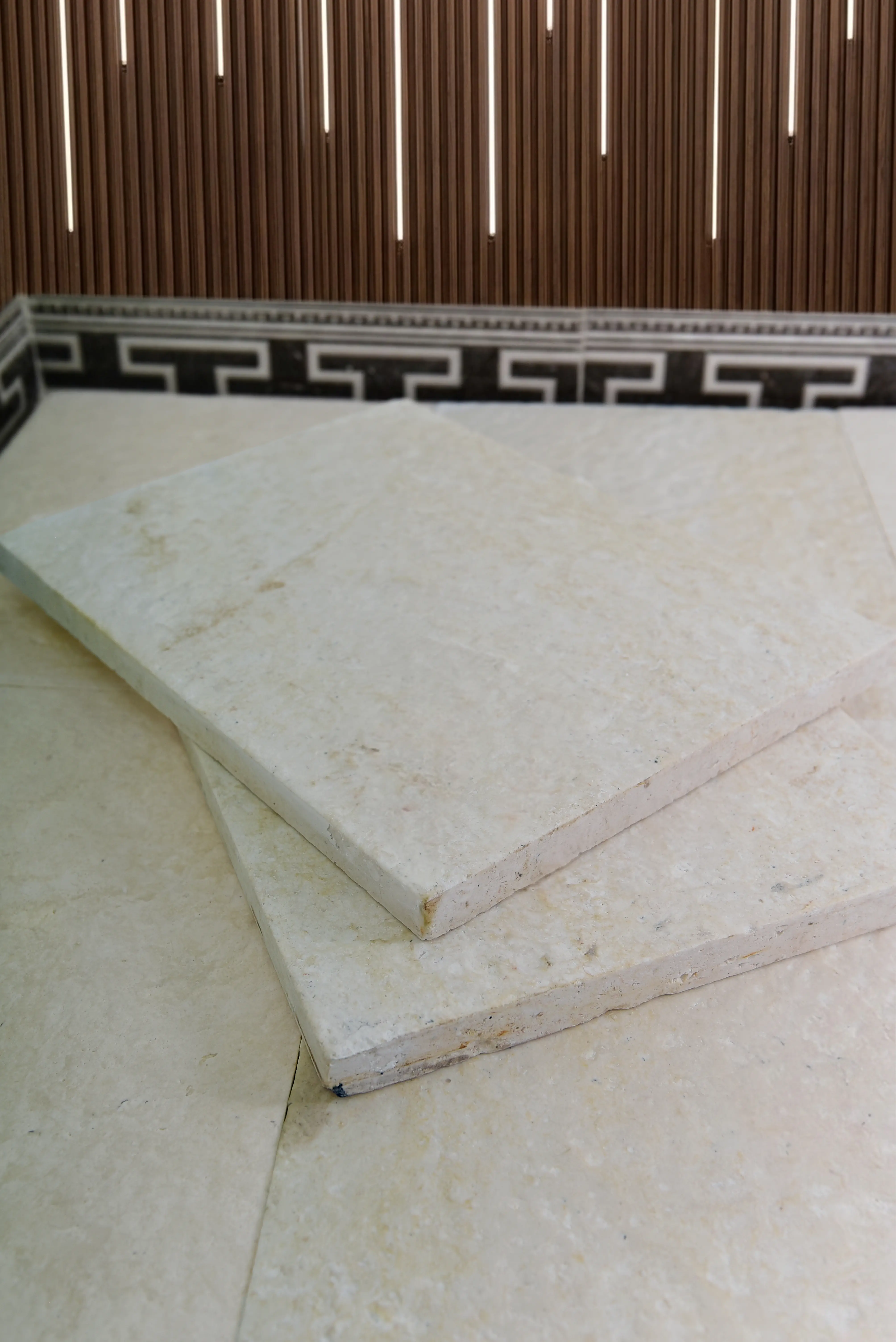 Close-up of pale beige natural stone tiles stacked and arranged for display, relevant to how to fill travertine holes.