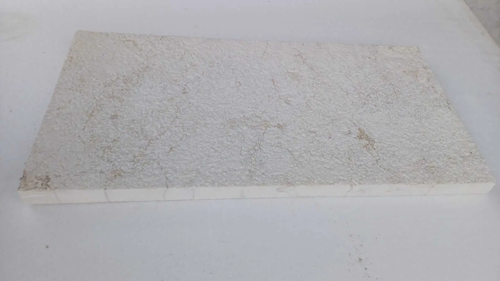 Close-up textured surface of a rectangular limestone slab with subtle cracks, relevant to is quartzite a natural stone.