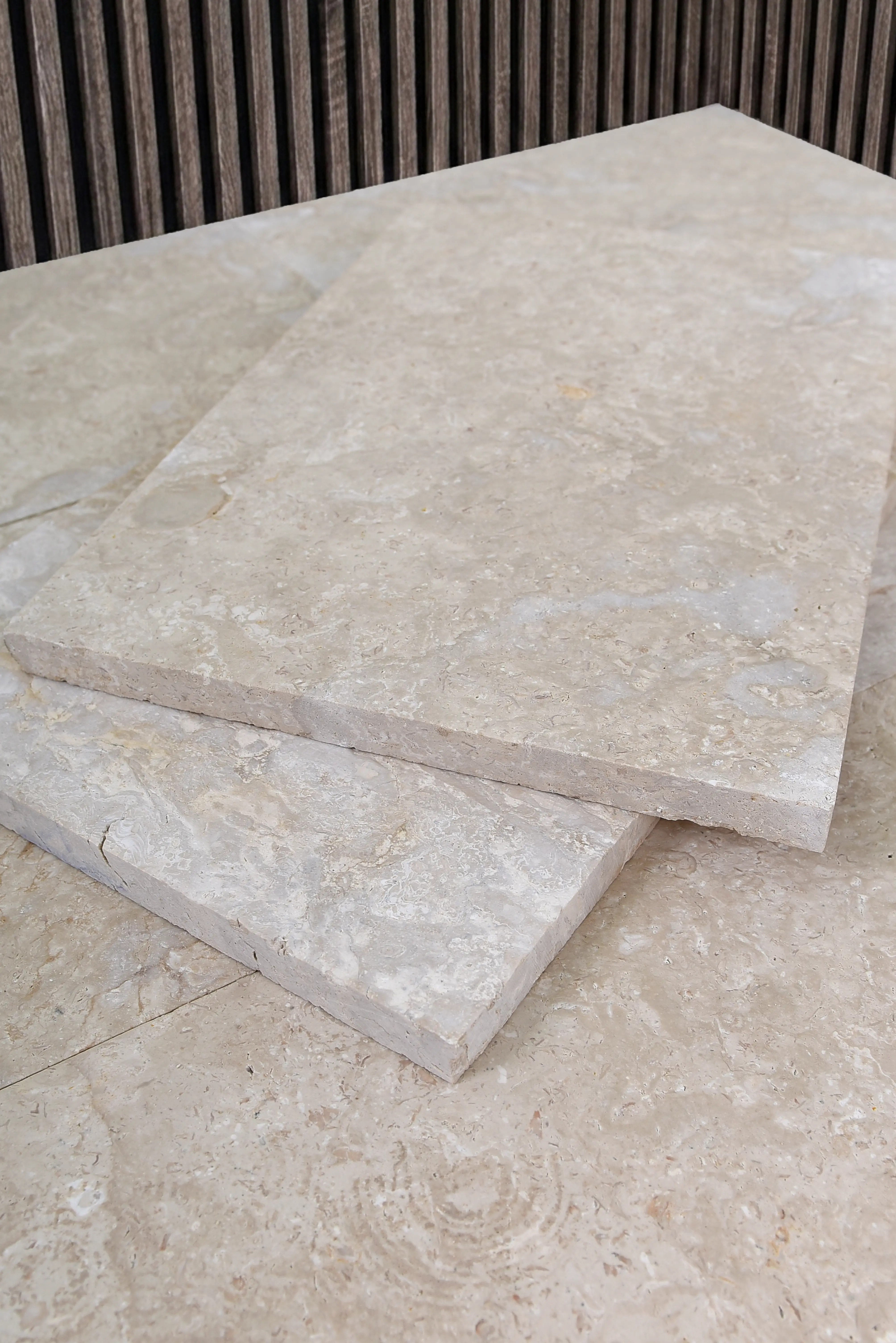 Two beige limestone slabs stacked on a textured surface, a reference for Masonry Stone Suppliers.