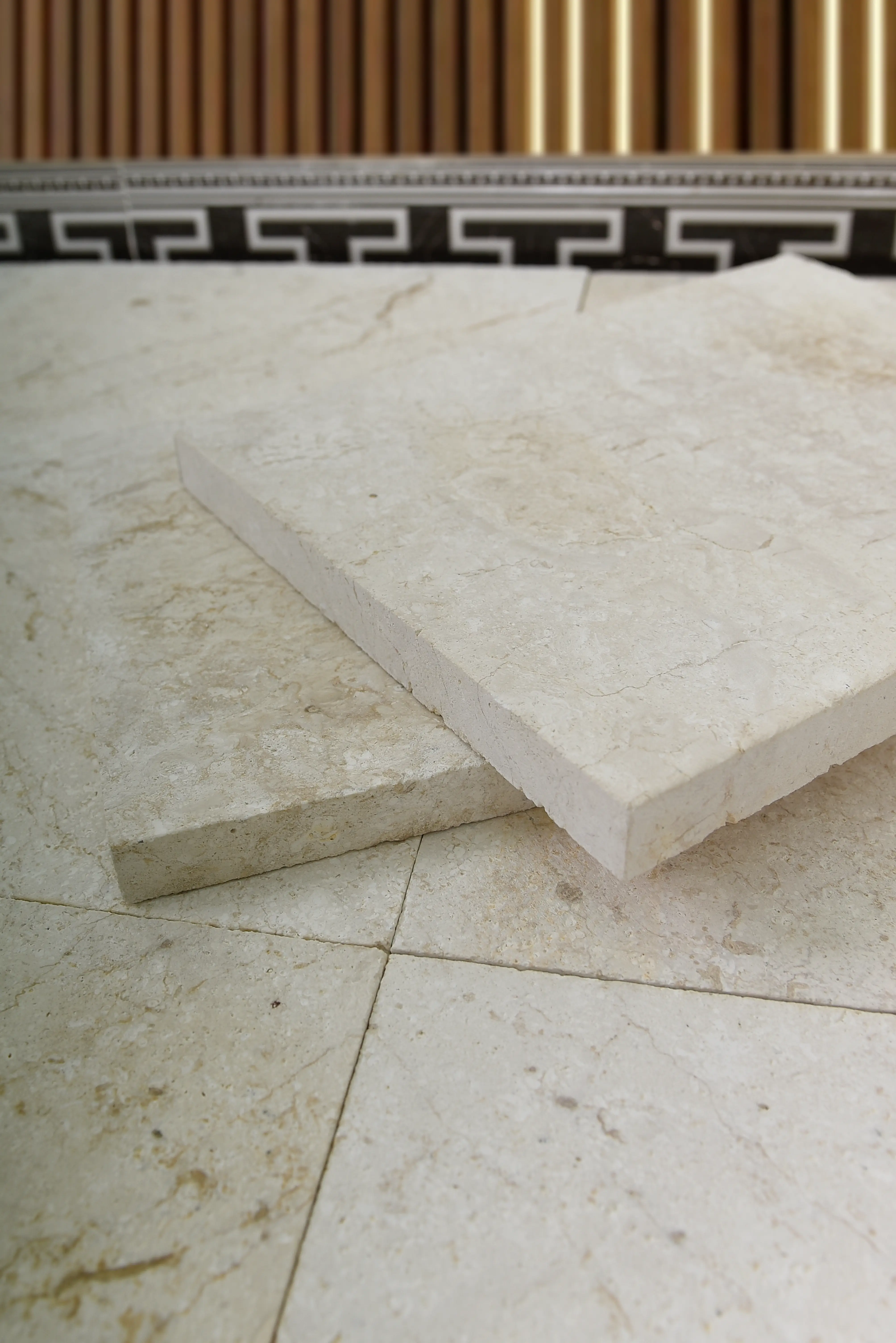 Close-up of cream colored stone pavers with subtle veining for natural stone flooring, an example for raised garden stone wall build.