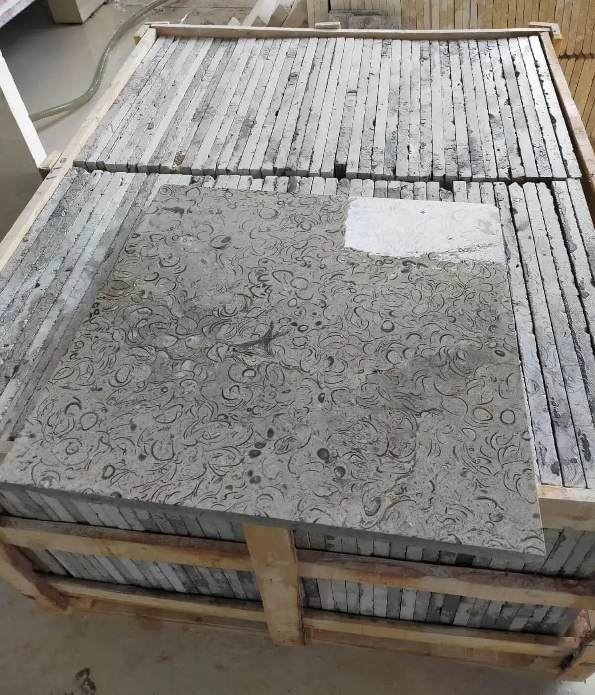Stacked Stone Slabs with Fossil Patterns Close-up view of fossil-patterned limestone pavers stacked in a wooden crate, relevant to railings for stone steps.