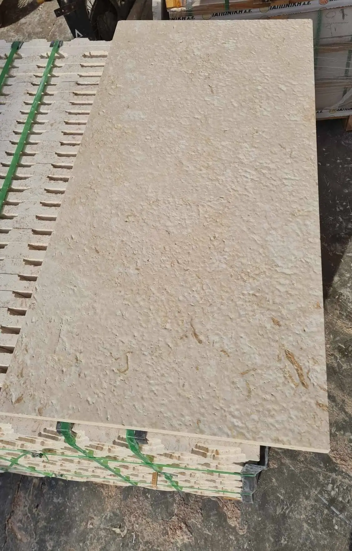 Close-up view of textured limestone slabs stacked and ready for use, shown for paver base material guide.