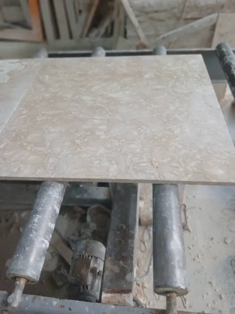 Stone Slab on Conveyor Rollers Polished beige limestone slab resting on industrial conveyor rollers at a fabrication facility, pictured for backyard decomposed granite design ideas.