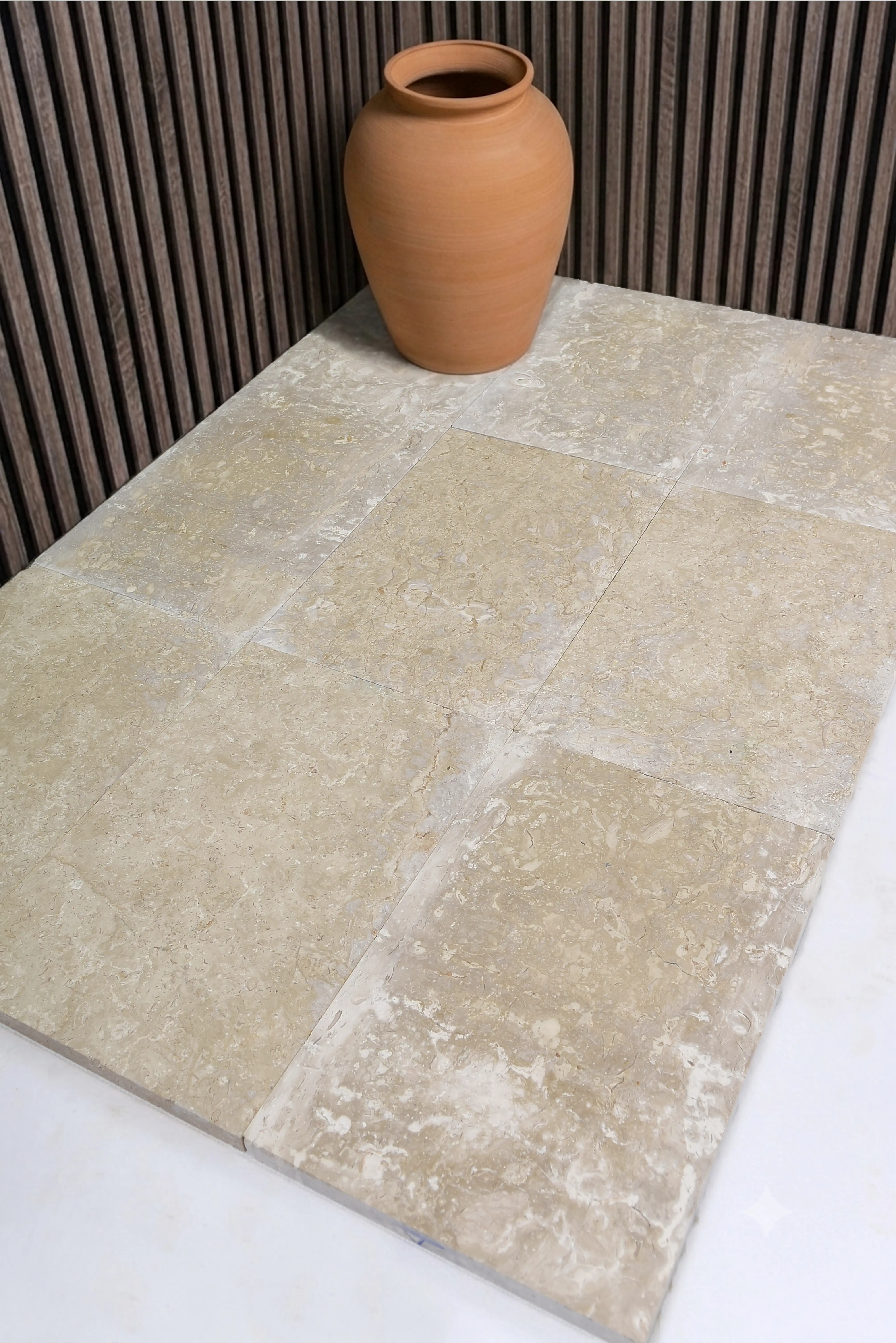 Warm beige flagstone tiles display natural veining and texture, a terracotta pot sits on top, a reference for Flagstone Suppliers.