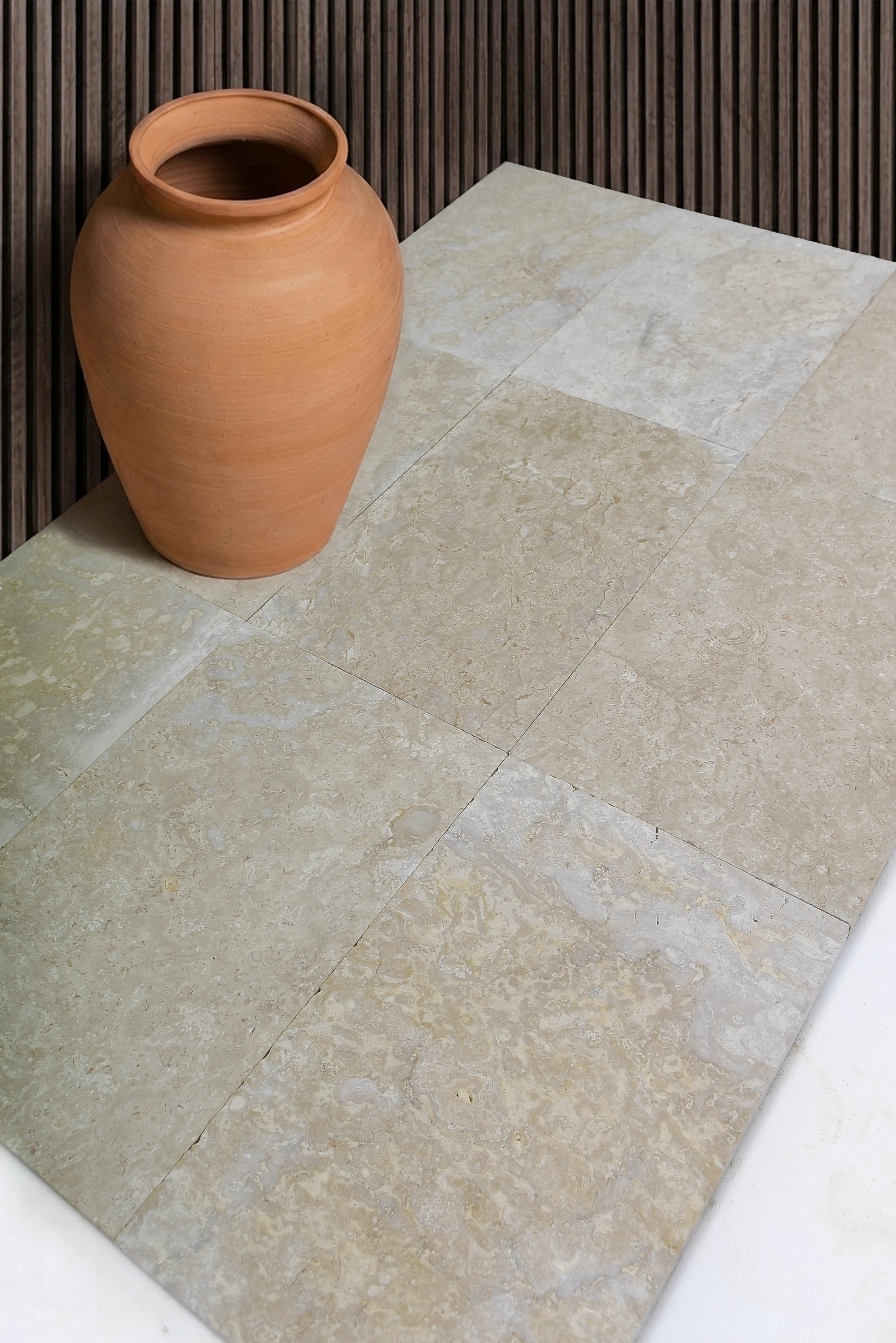 Terracotta Pot on Stone Tiles A rustic terracotta pot sits on a warm-toned travertine tile floor, shown for crushed granite landscape guide.