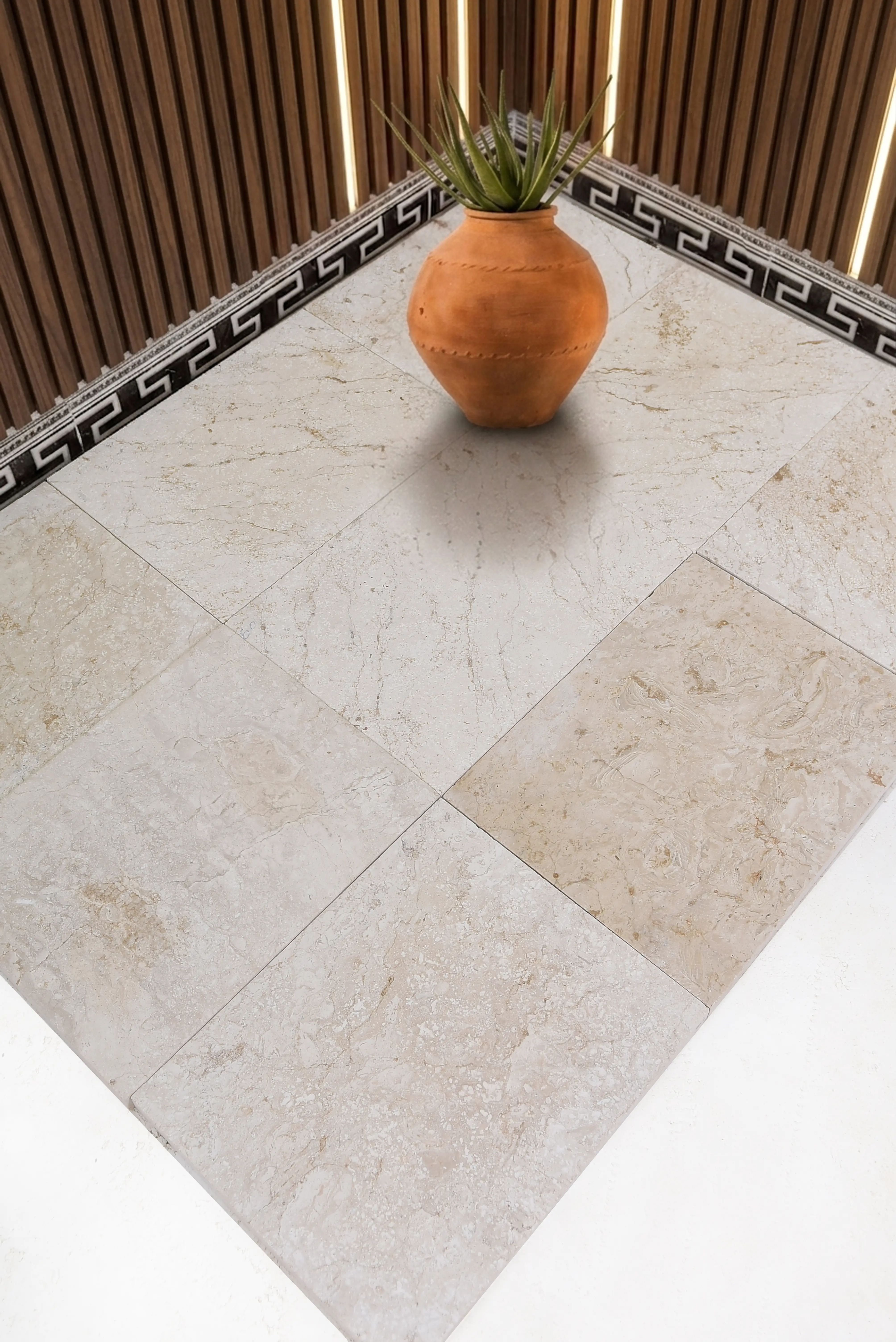 A terracotta vase with a plant sits on a polished marble floor, relevant to paver patio retaining wall guide.