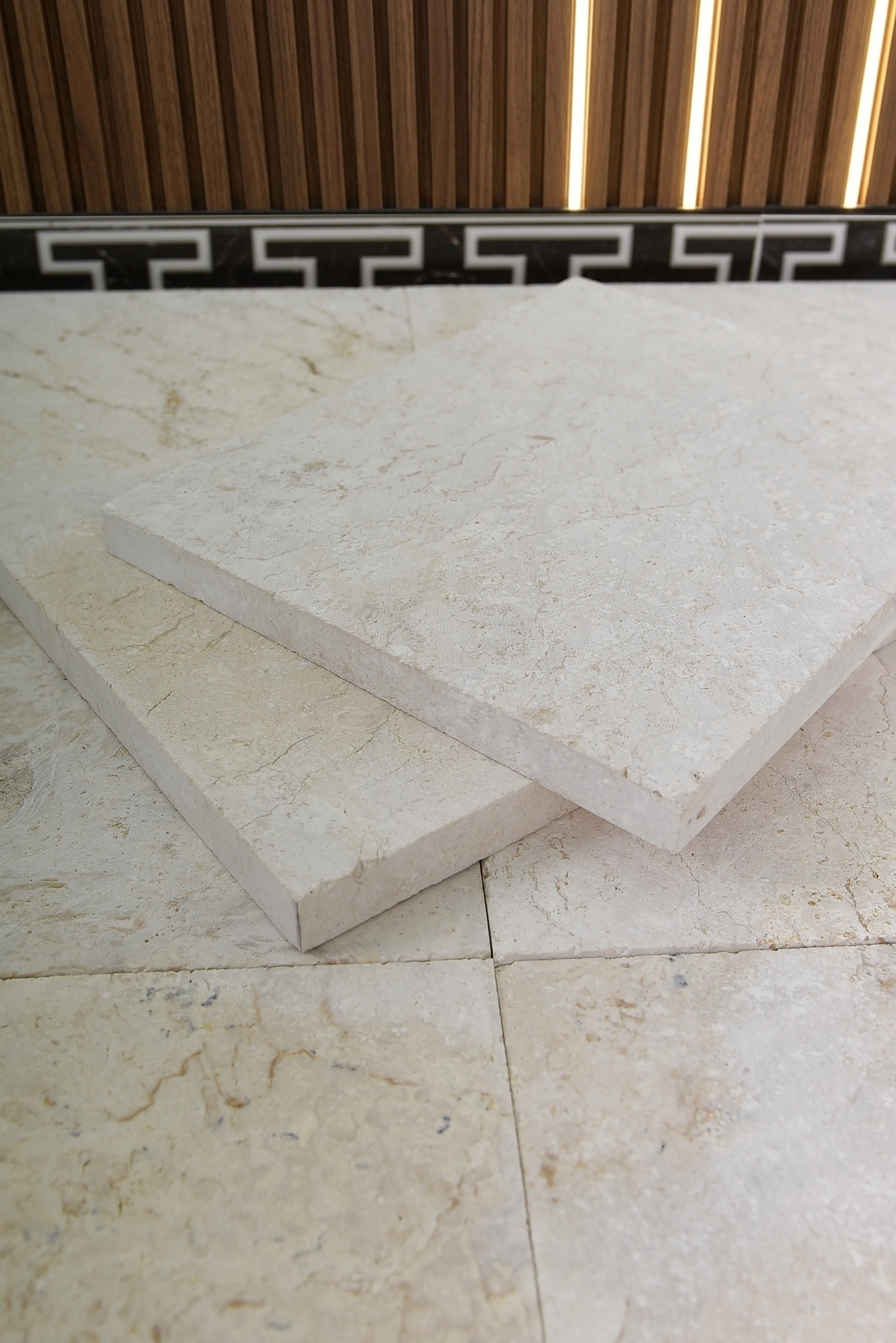 Close-up view of light beige limestone slabs with natural texture and veining, an example for shower floor tile ideas.