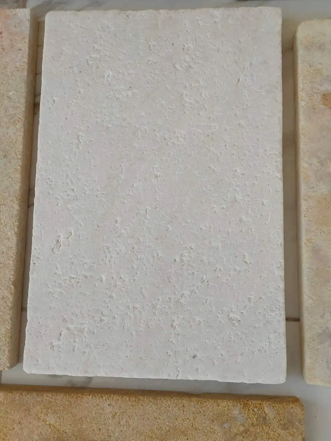 Close-up view of a textured cream stone tile showing its porous surface, pictured for how to build stone masonry wall.