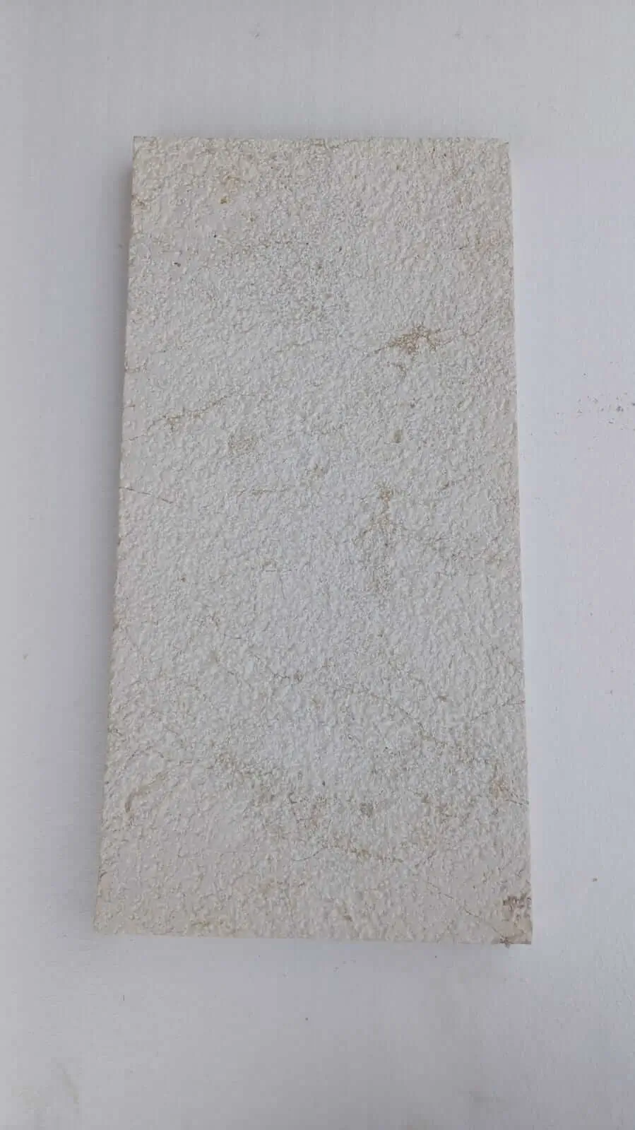 Light-colored limestone slab with a textured, speckled surface detail, relevant to how to build stone masonry wall.