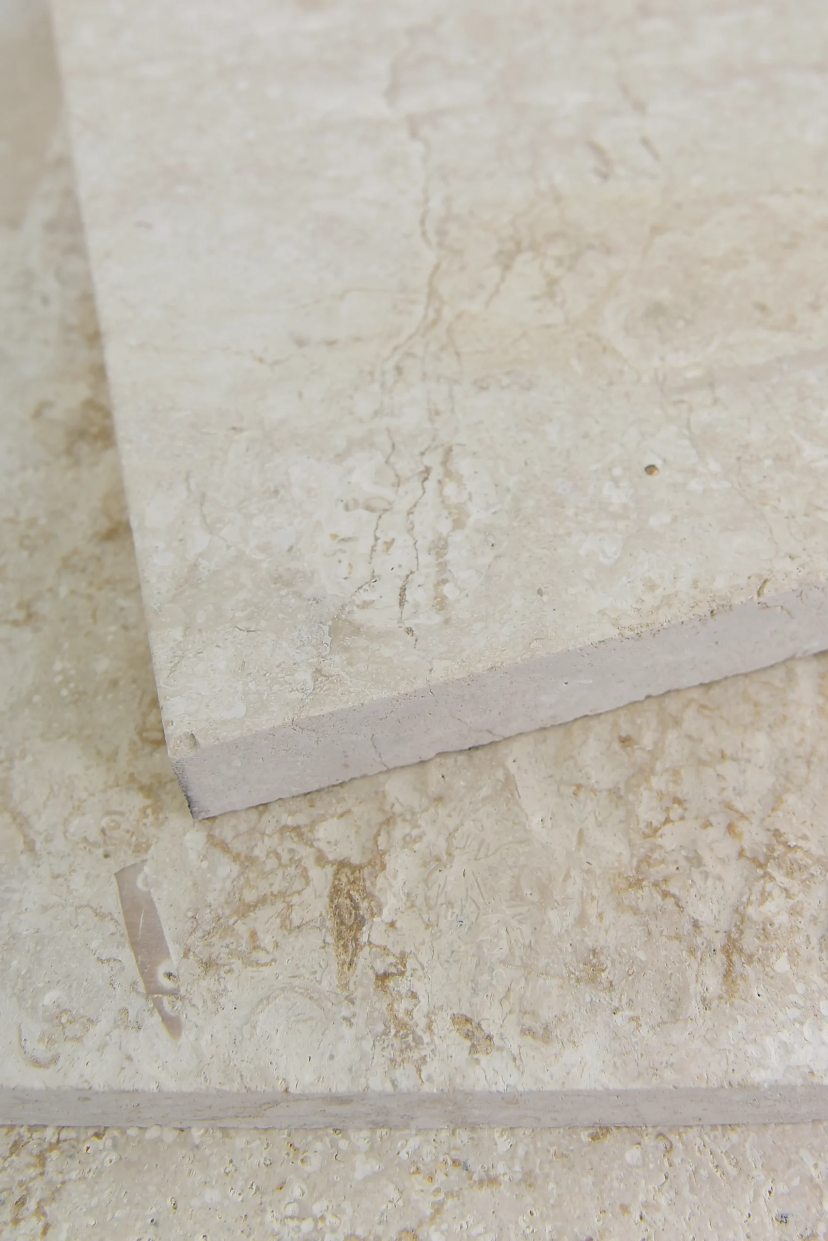 Close-up view of a light travertine surface texture with natural pitting, pictured for sealer for travertine.