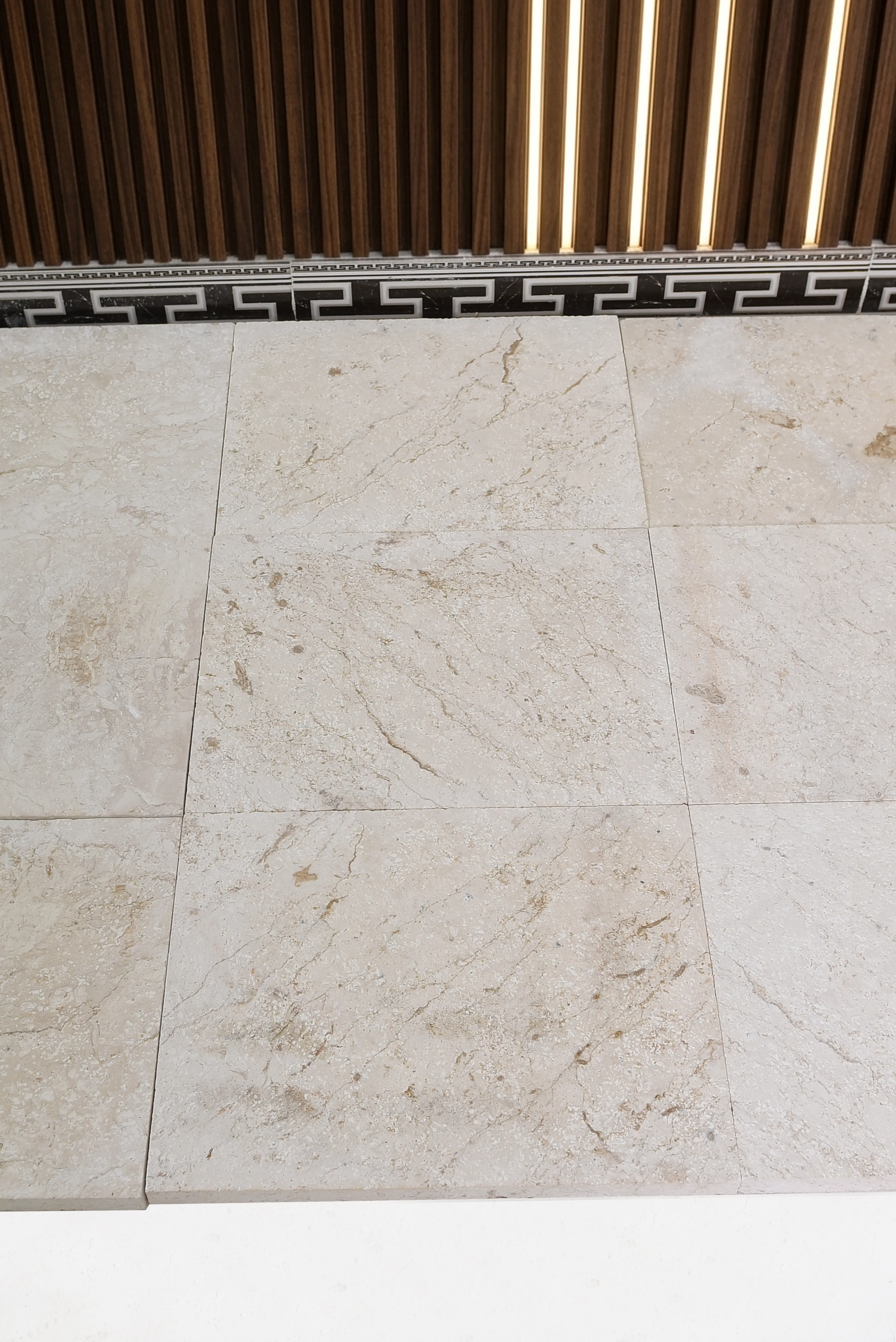 Close-up of beige travertine floor tiles showing natural veining and texture variations, a reference for large tile lippage problems.