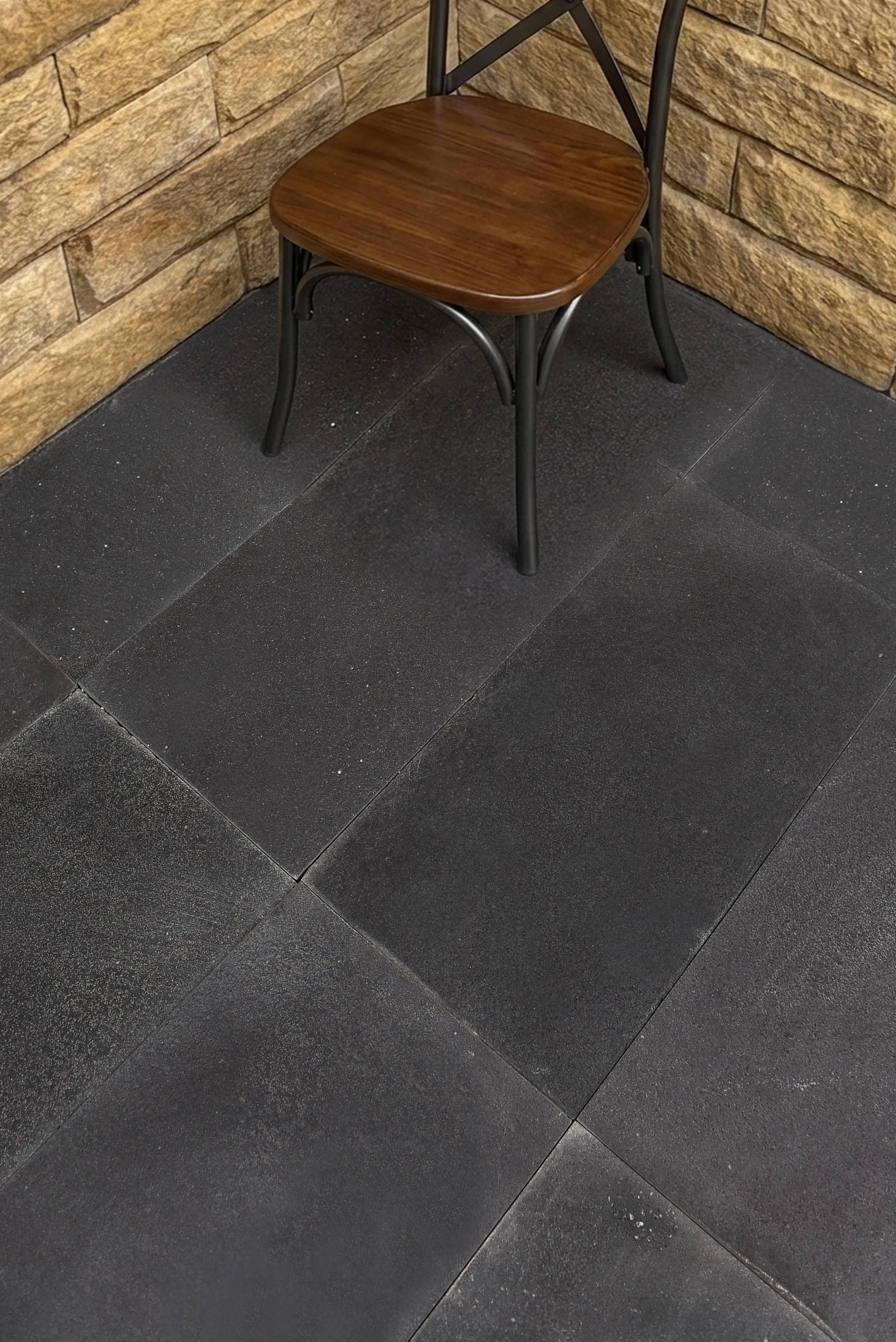 A dark rubber floor with a wooden chair, perfect for travertine pavers, shown for 6x12 Travertine Tile.