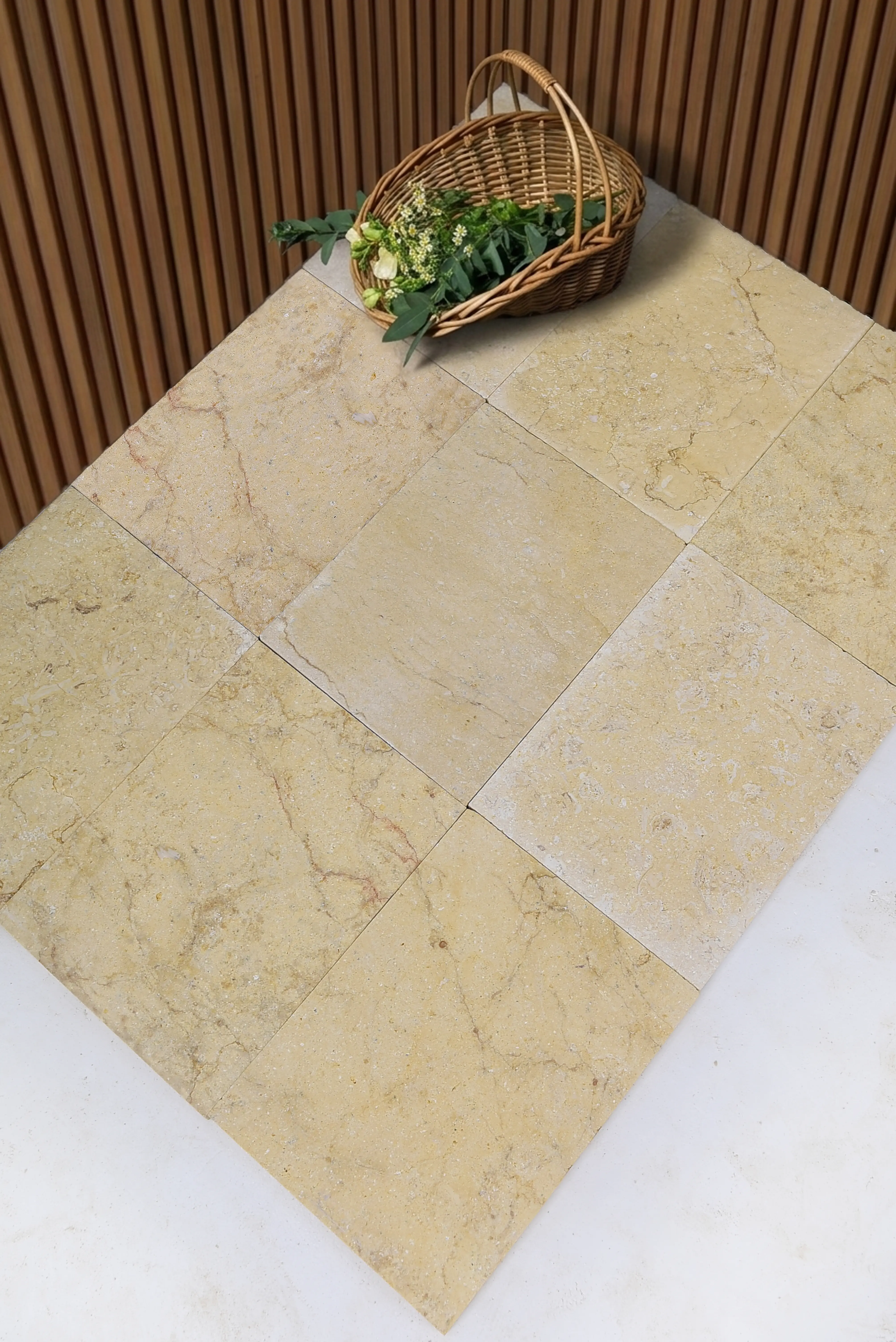 A woven basket filled with white flowers rests on a surface of beige natural stone tiles, relevant to stone masonry apprenticeship.