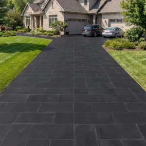 Long driveway paved with black rectangular stone pavers leading to a large two-story suburban brick house.