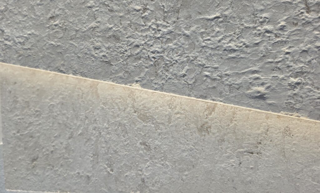 Sawn edge meeting 16 grit brushed antiqued limestone surface