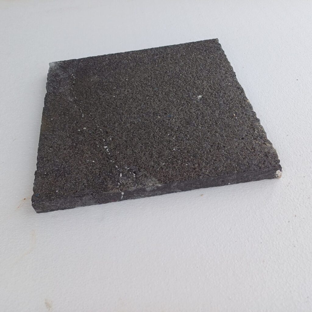 Bush-hammered black basalt paver at an angle