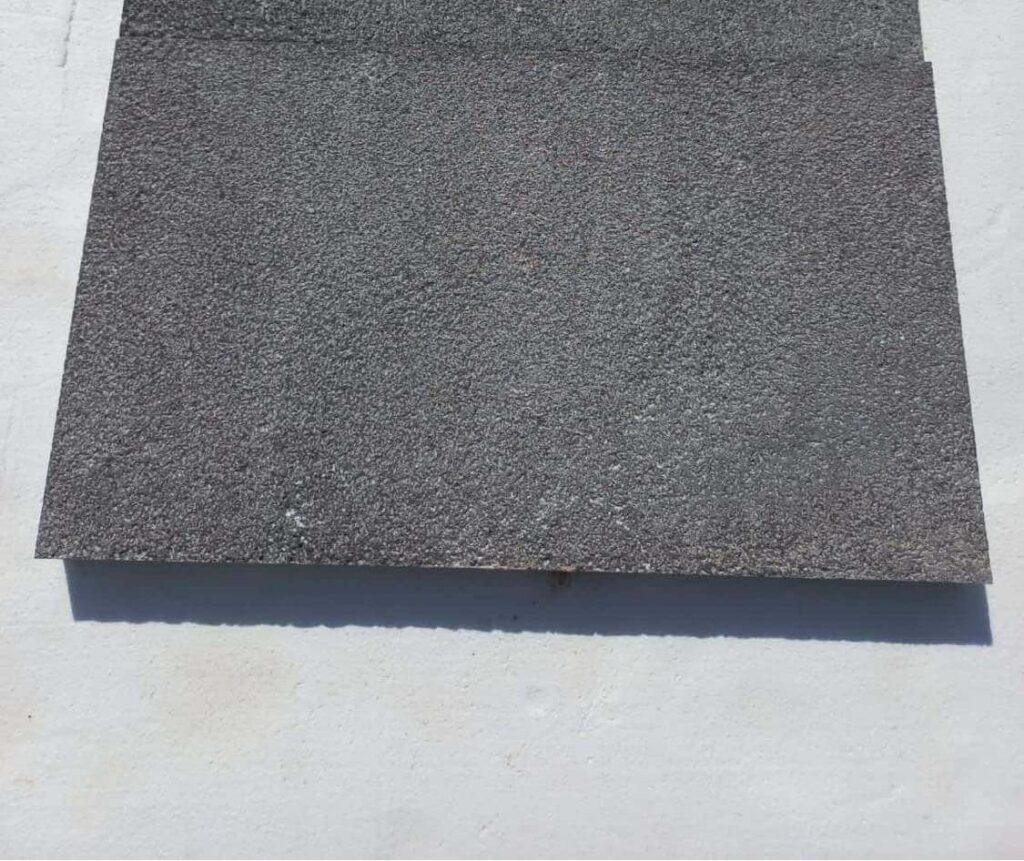 Stacked bush-hammered black basalt pavers showing texture and edge