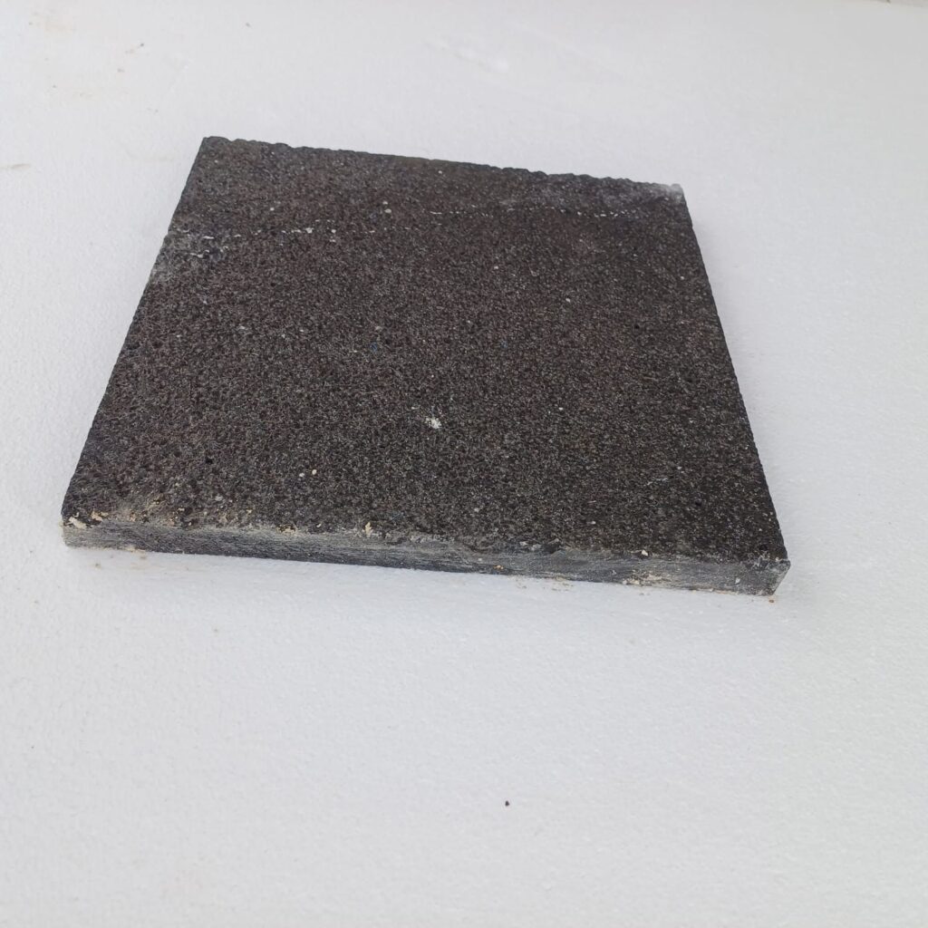 Bush-hammered black basalt paver showing thickness