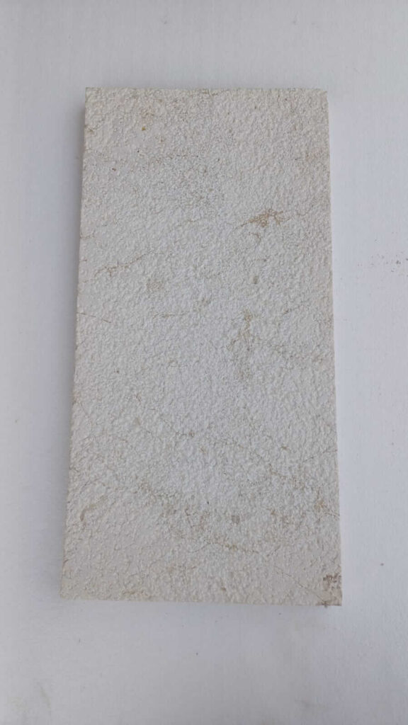 Bush-hammered white limestone paver with uniformly pocked surface