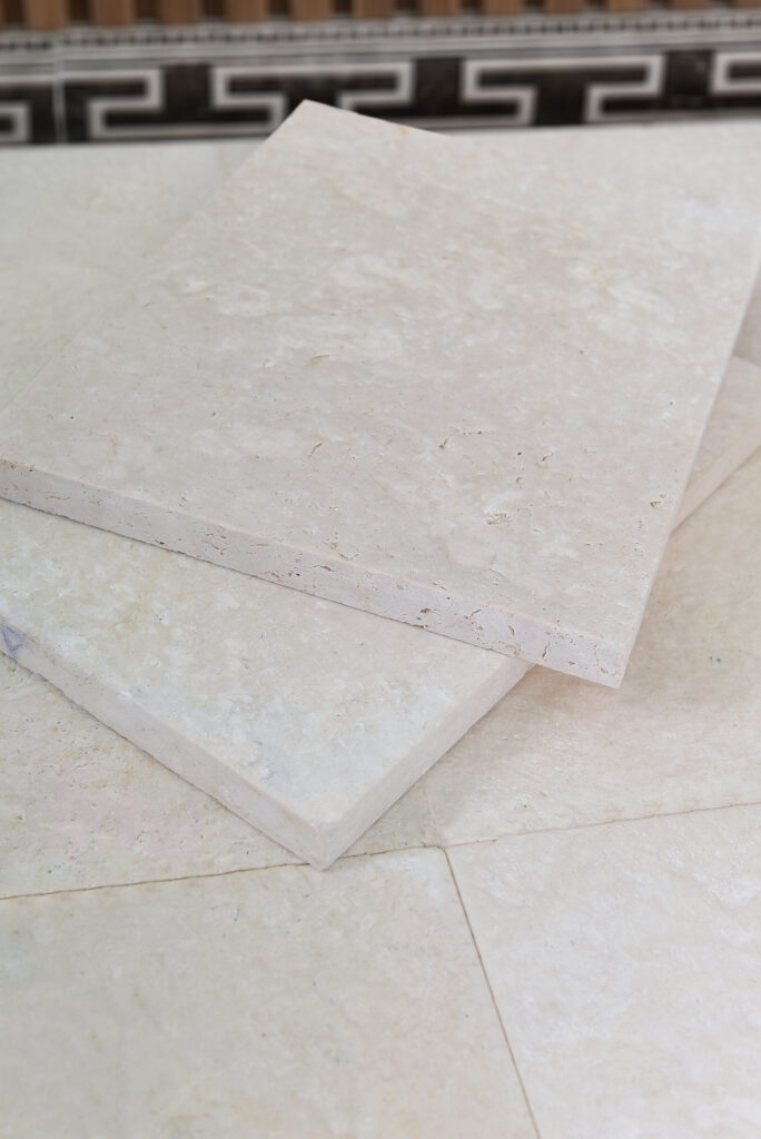 Double-brushed 24 grit limestone tiles stacked in the showroom with mosaic border behind