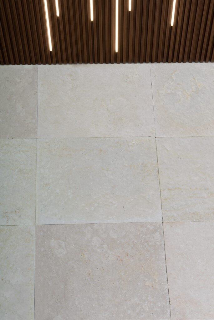 Double-brushed 60 grit limestone flooring display with slat-wall backdrop
